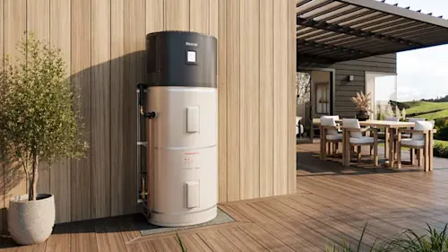 White cylindrical heat pump unit installed outside modern home with glass doors and green plants nearby.