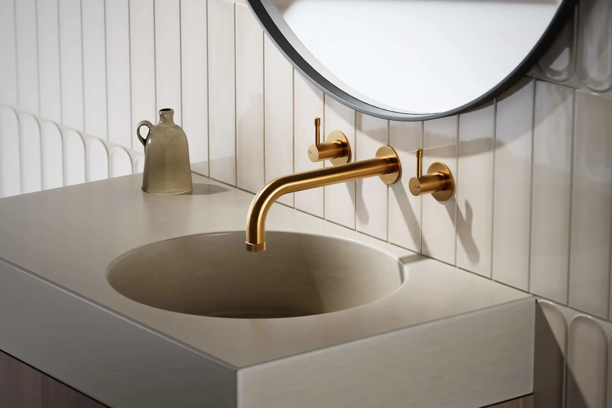 Bathroom sink with brass wall-mounted faucet, round mirror, and white tiled wall with decorative vase on counter.