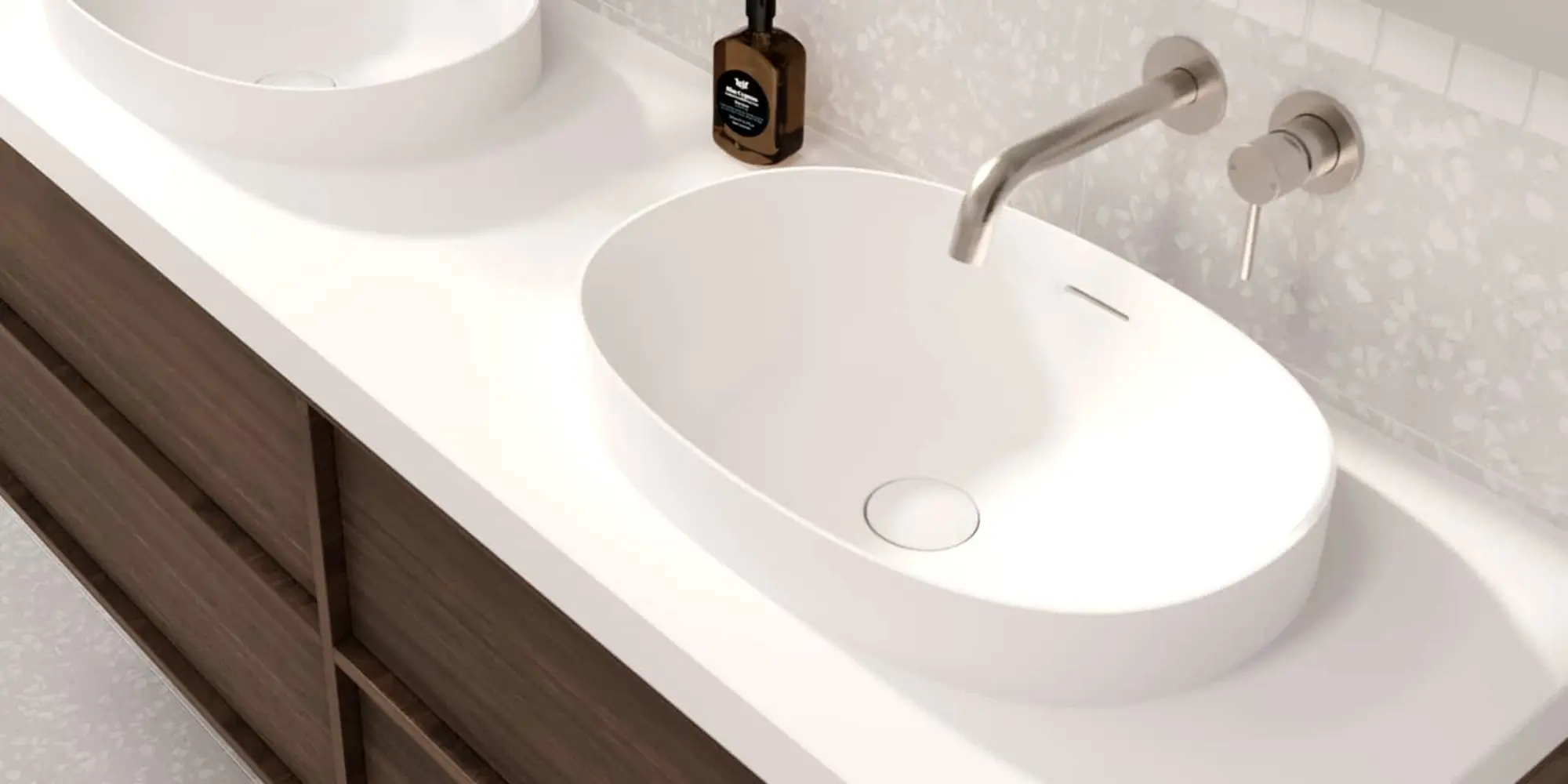 White oval sink on bathroom vanity with wall-mounted brushed nickel faucet and soap dispenser