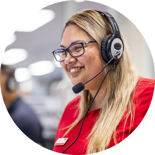 Woman wearing headset and glasses smiling in red shirt in office setting