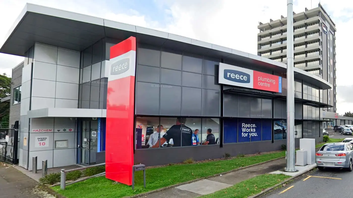 Modern Reece plumbing centre storefront with red and blue signage, grey exterior, and glass windows showing interior.