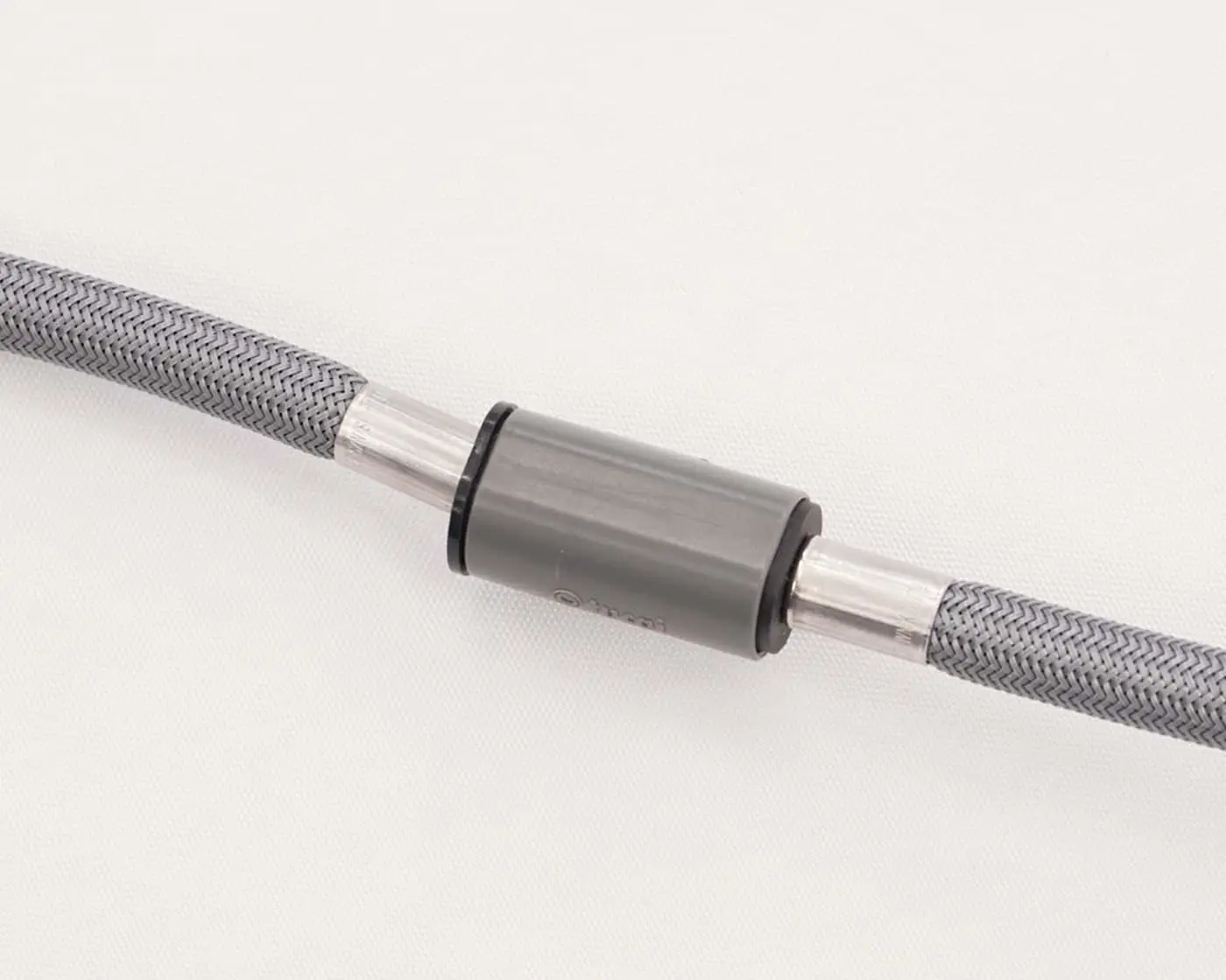 Gray braided hose with metal connector and clear plastic ends on white background