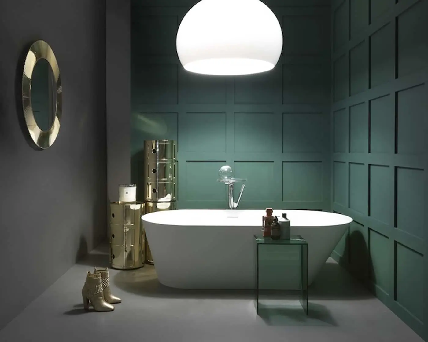 Modern bathroom with white freestanding tub, dark green paneled walls, round mirror, and white dome pendant light.