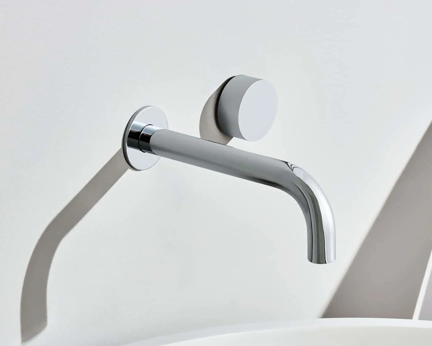 Wall-mounted chrome faucet with a single handle and curved spout against a white background.
