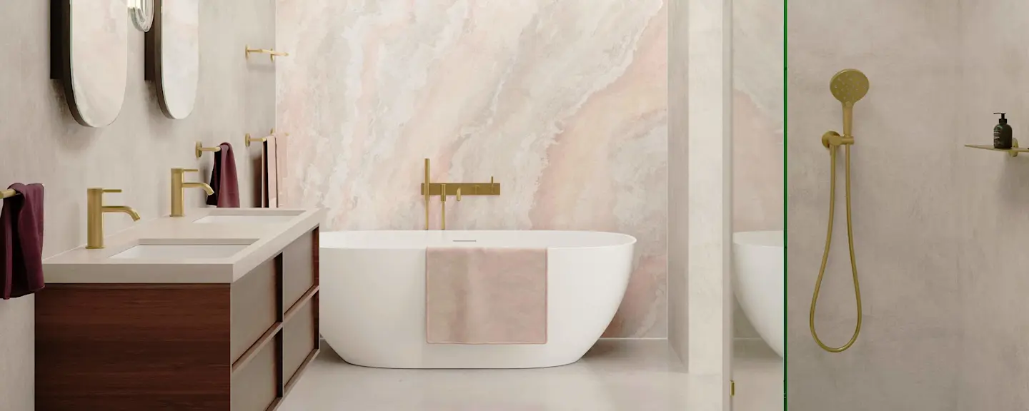 Modern bathroom with white freestanding tub, pink marble wall, brass fixtures, wooden vanity, and glass shower enclosure.