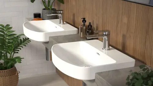 Modern bathroom with two white vessel sinks on gray countertop, wood cabinetry, chrome faucets, and green plants.