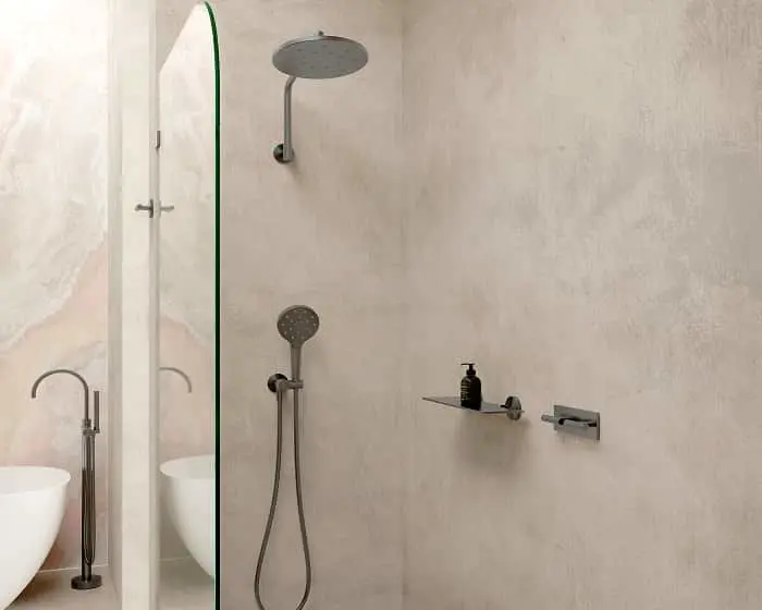 Modern bathroom with glass shower partition, rainfall showerhead, handheld shower, white sink, and beige textured walls.