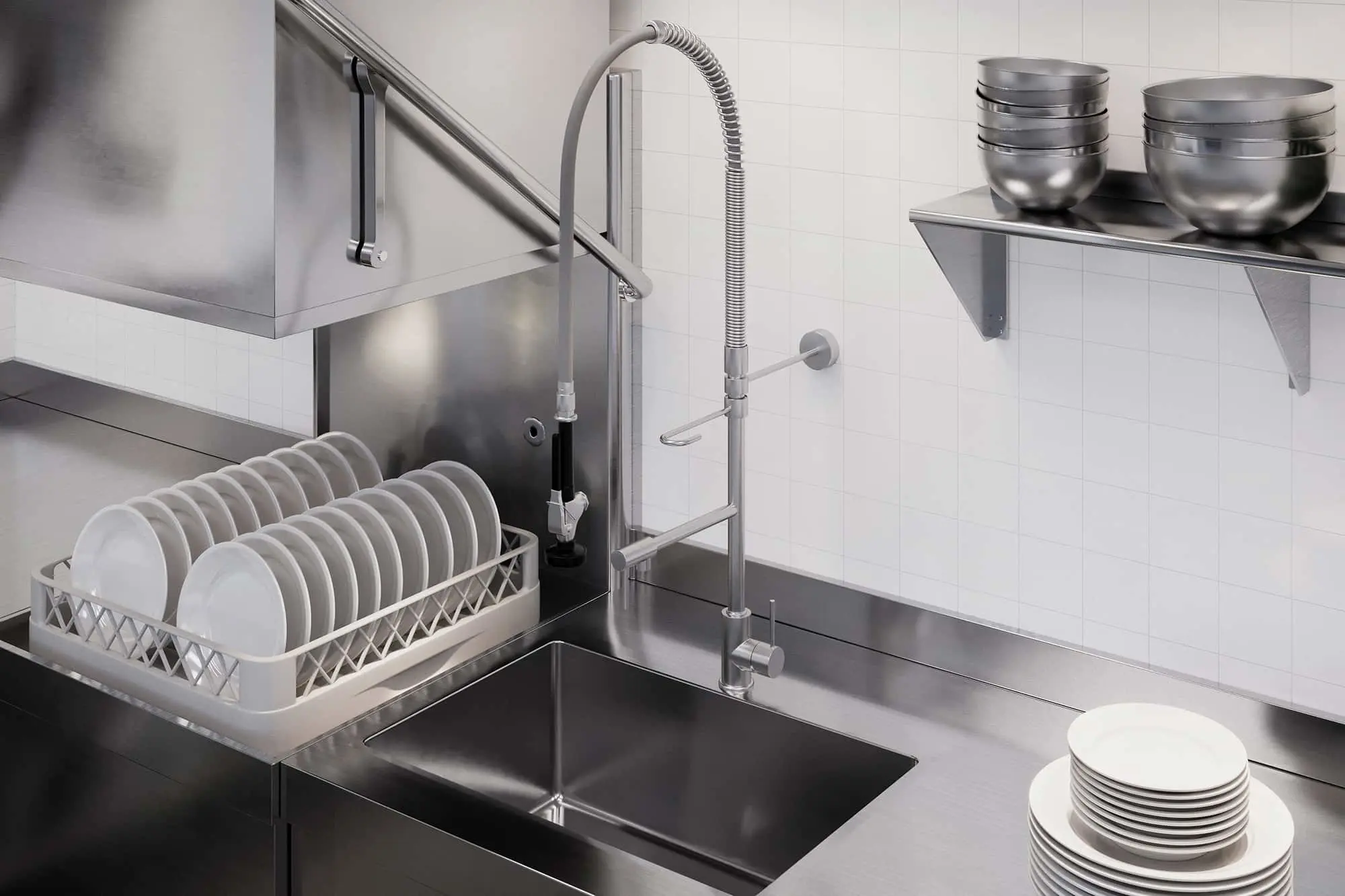 Commercial kitchen sink with stainless steel faucet, dish rack with white plates, and metal bowls on wall shelf.