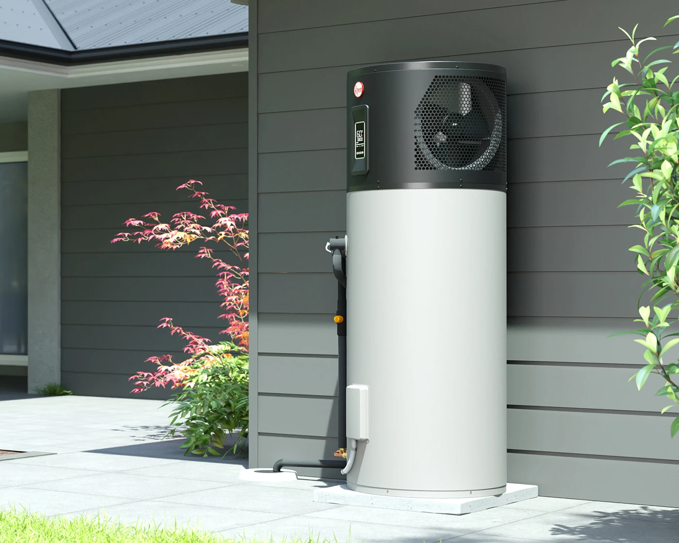 Heat pump water heater with black top and white tank installed outside a gray house with plants nearby.