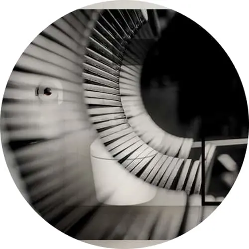 Black and white spiral staircase viewed from above, creating a curved geometric pattern with radiating steps.