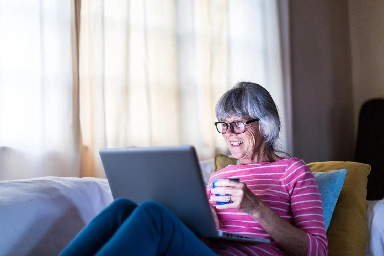 Lady on a sofa using a laptop smiling