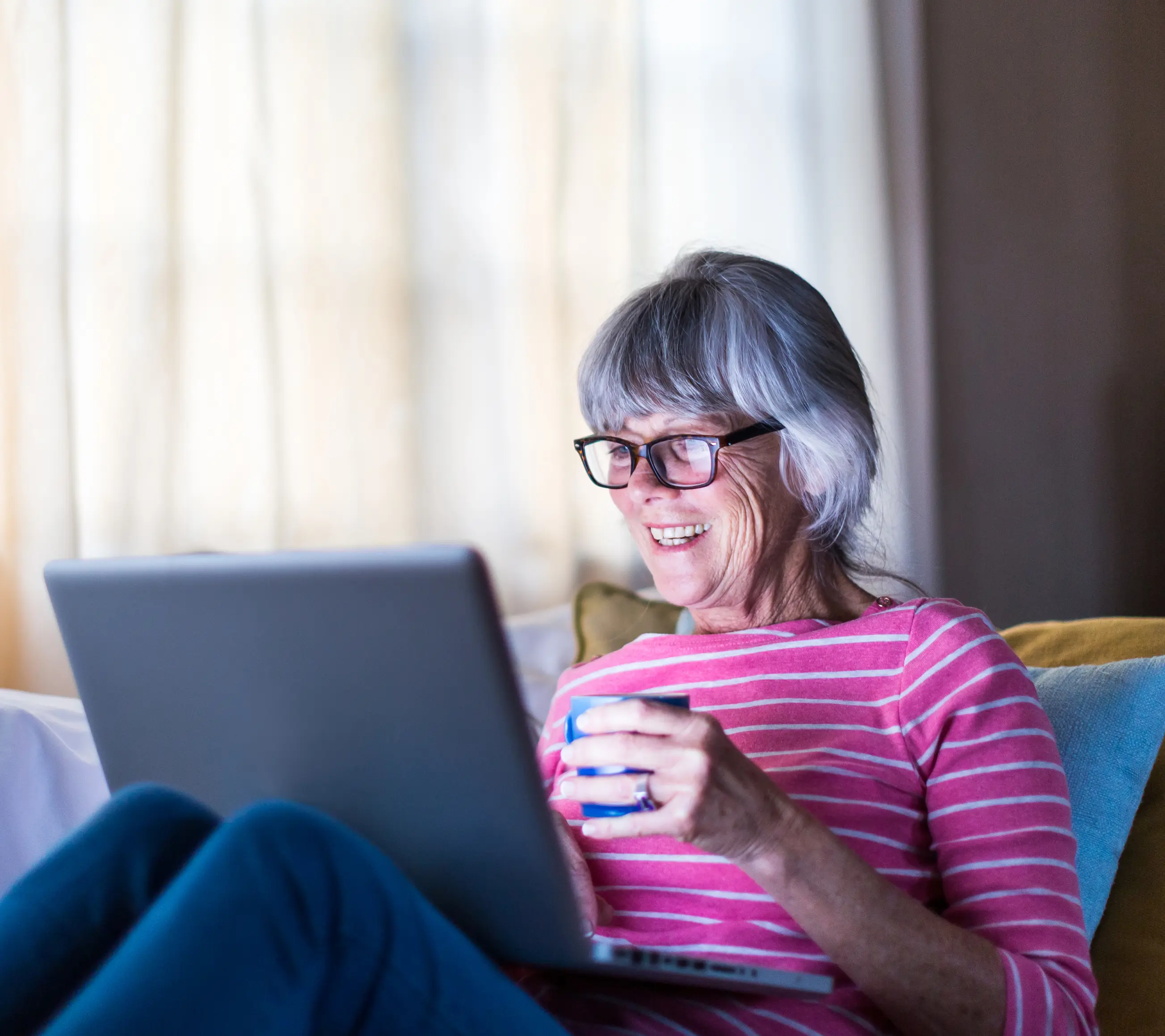 woman drinking a cup of tea using a laptop