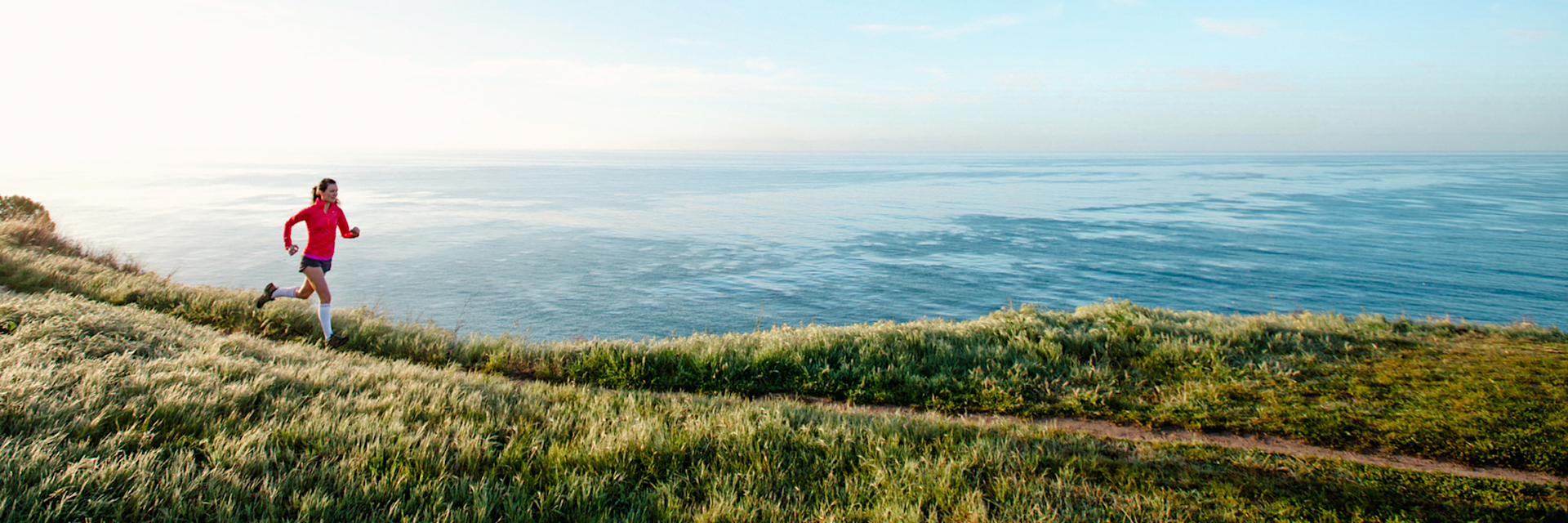 Woman running along grassy coast