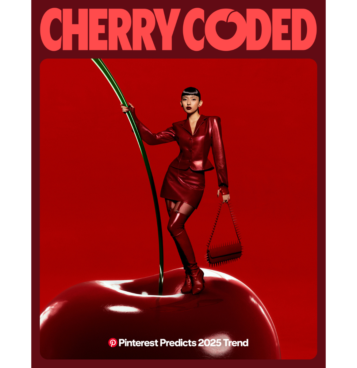 Woman in latex cherry red dress and boots stands on top of large cherry on red backgound