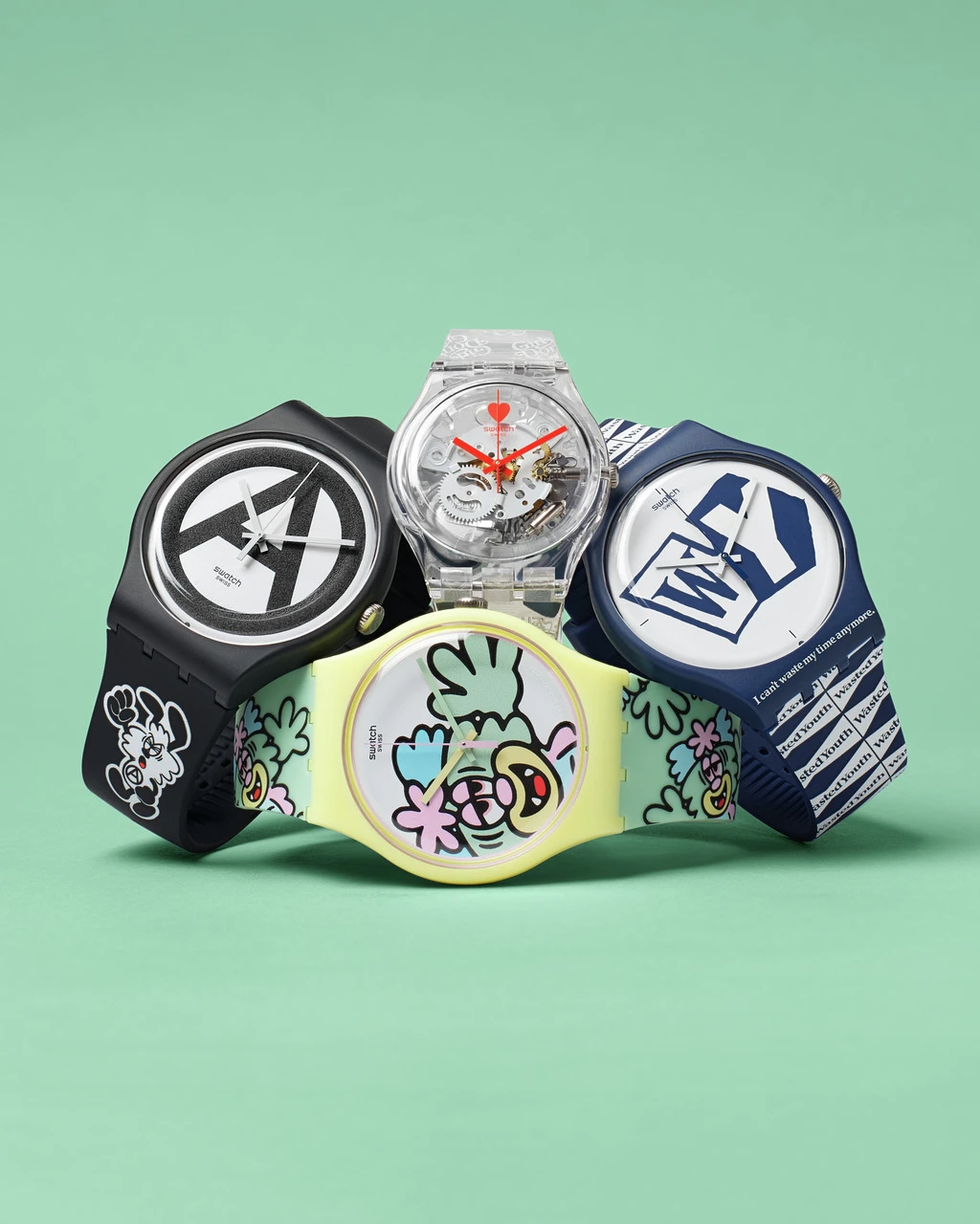 A collection of four unique and colorful wristwatches with artistic designs, displayed against a solid green background.