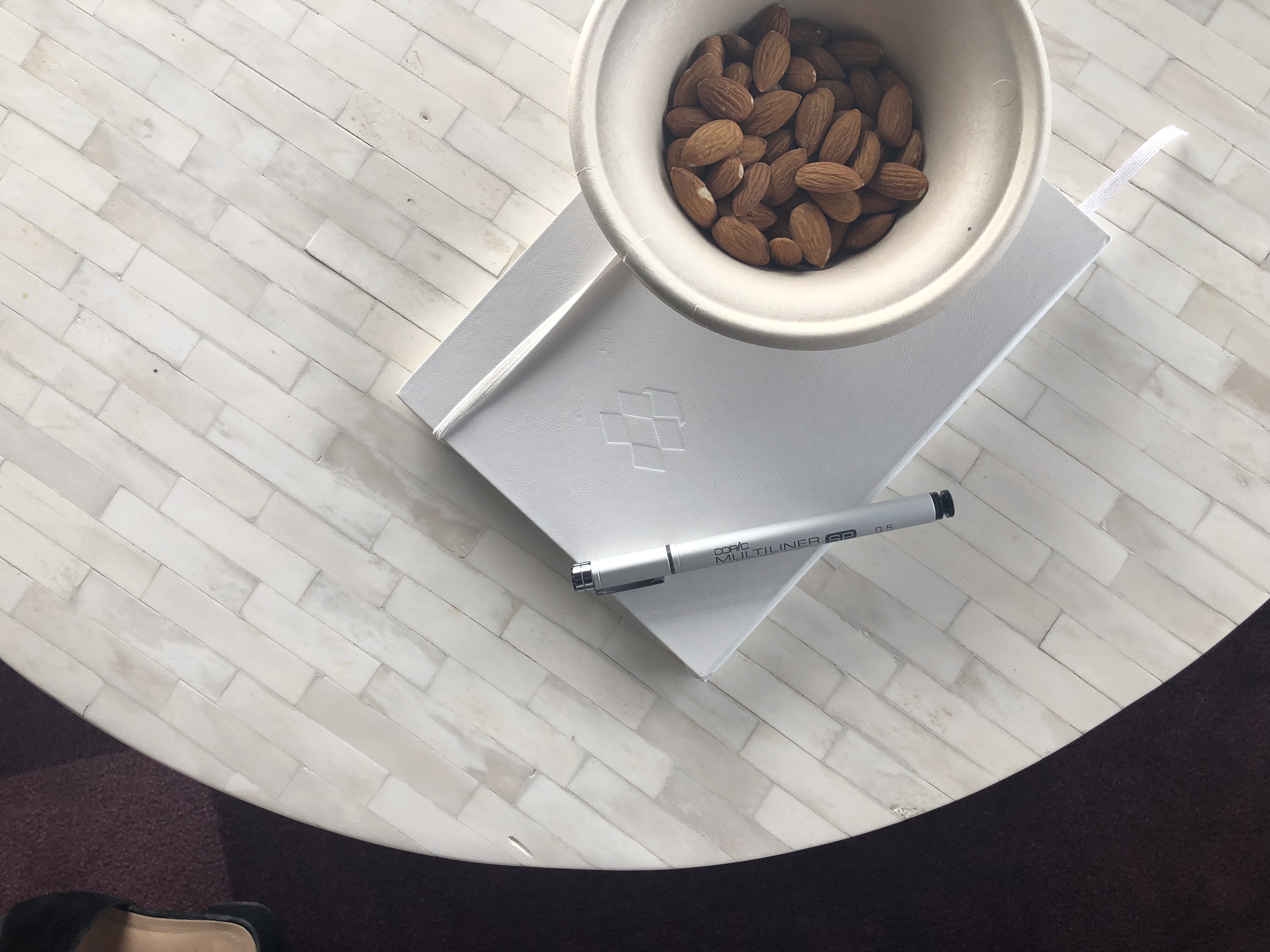 Almonds in a paper cup on a white notebook embossed with Dropbox's logo.