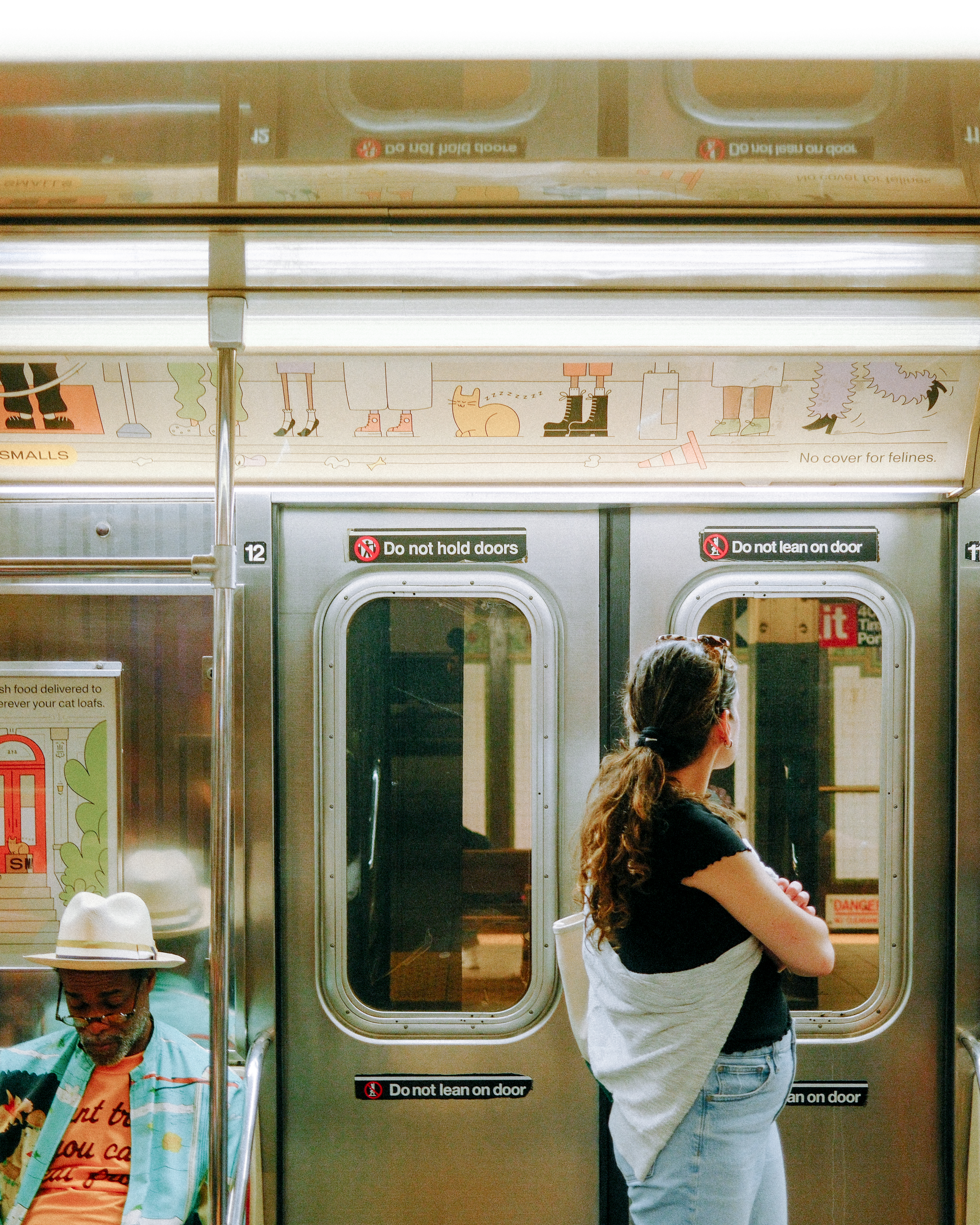 A photo of the doors of the subway from the interiors, with Smalls ads along the top and the middle of the car.