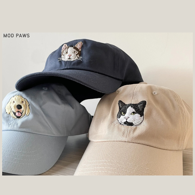 The image shows three baseball caps with embroidered animal faces on the front. The caps have a clean, minimalist look, and the embroidery is detailed, capturing the animals’ facial features in a stylized yet recognizable way.