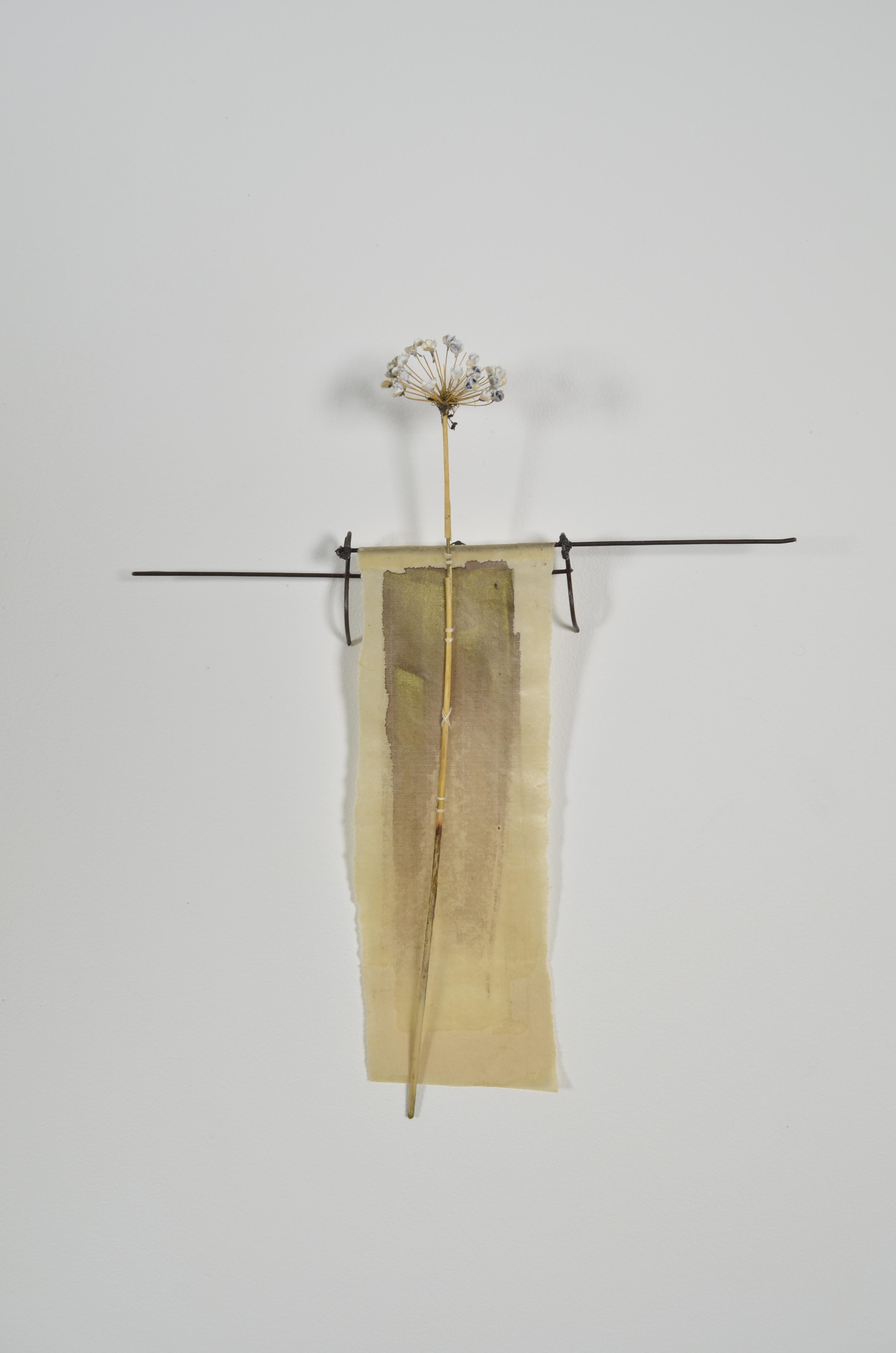 Unbleached mulberry paper with water color is sealed in encaustic, wrapped liked a paper doll dress over the found fence section of arms with an allium sealed in encaustic is sewn on top of the dress.