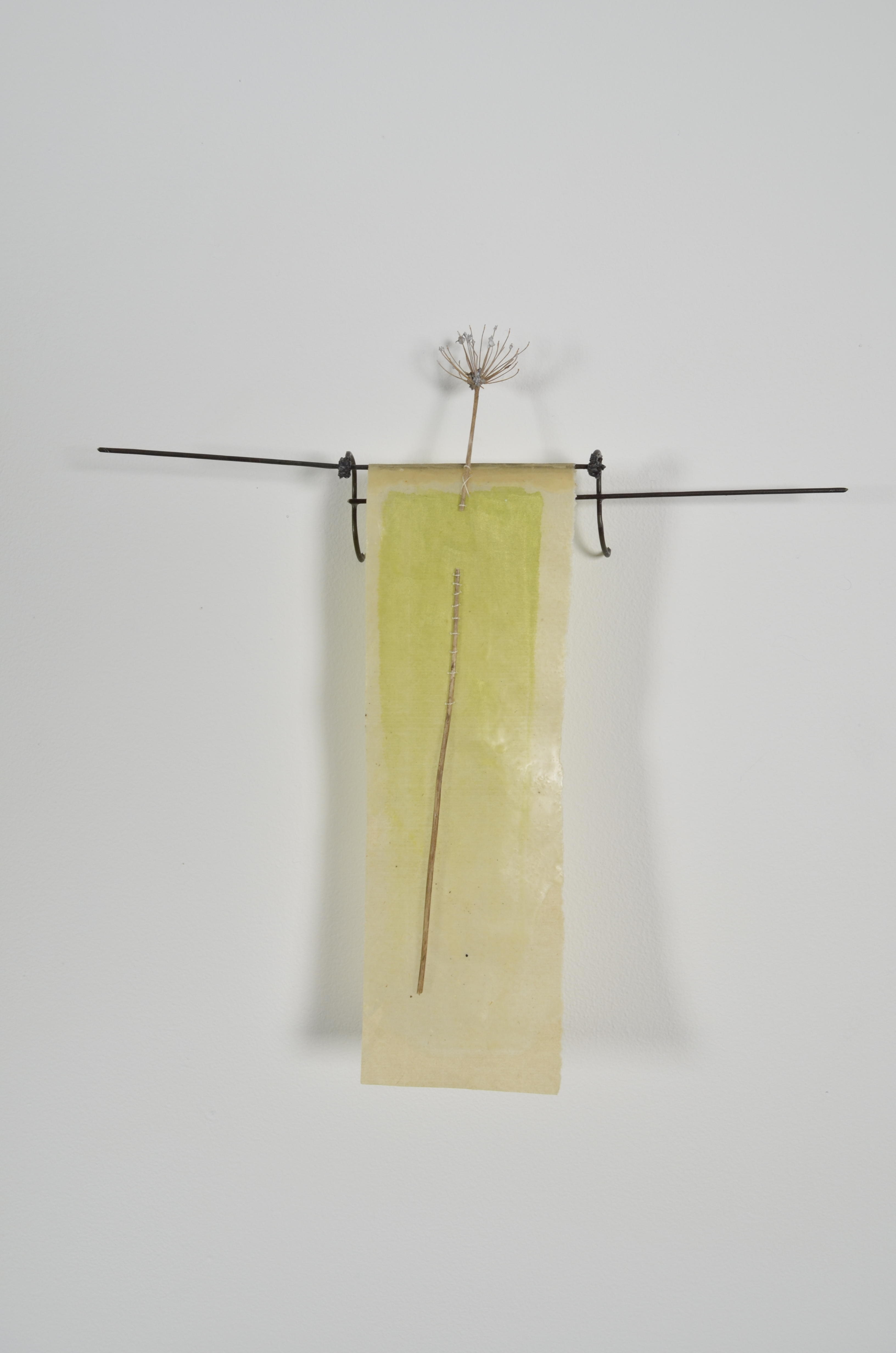 Unbleached mulberry paper with water color is sealed in encaustic, wrapped liked a paper doll dress over the found fence section of arms with an allium sealed in encaustic is sewn on top of the dress.