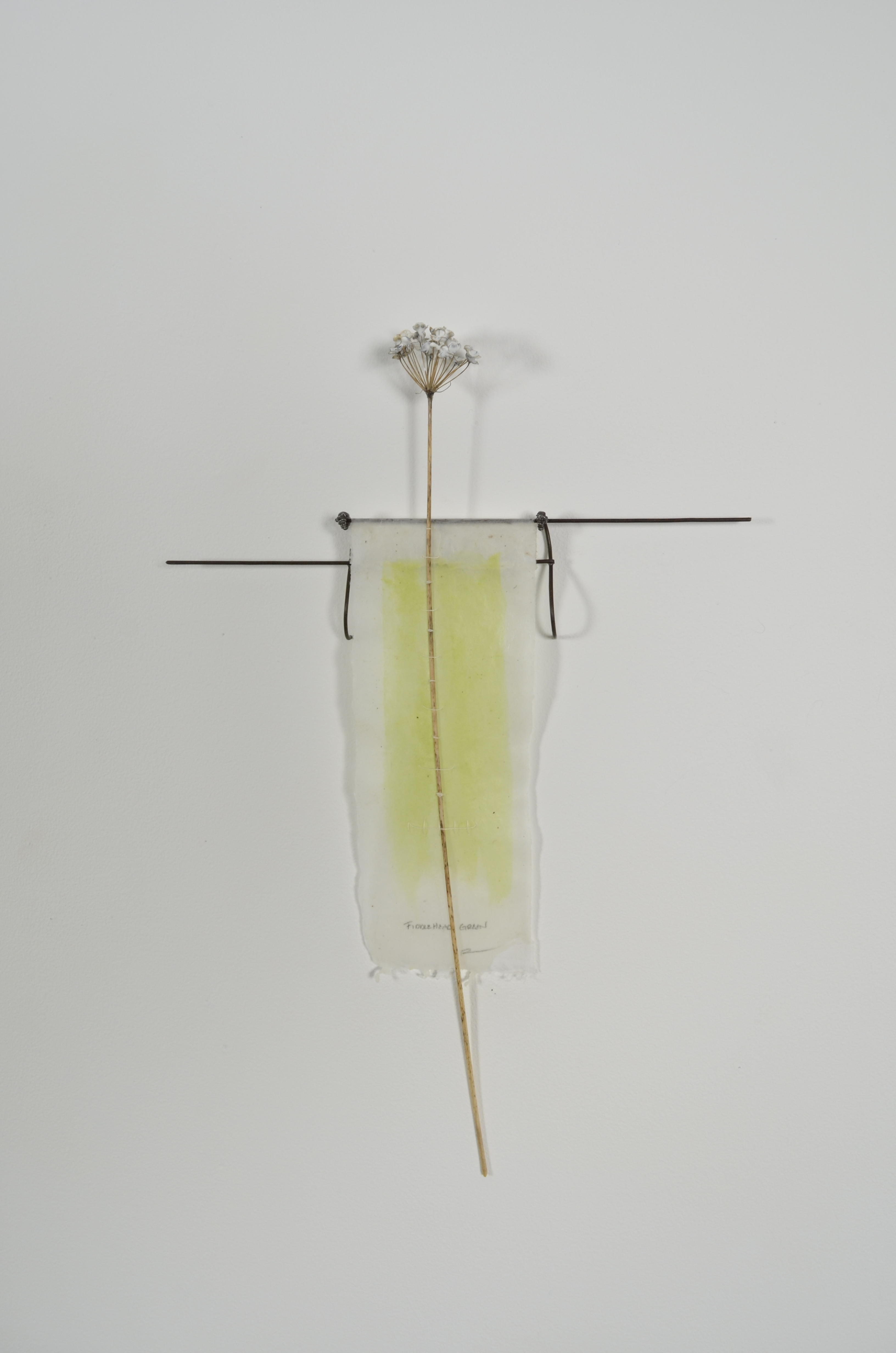 Bleached mulberry paper with water color is sealed in encaustic, wrapped liked a paper doll dress over the found fence section of arms with an allium sealed in encaustic is sewn on top of the dress.