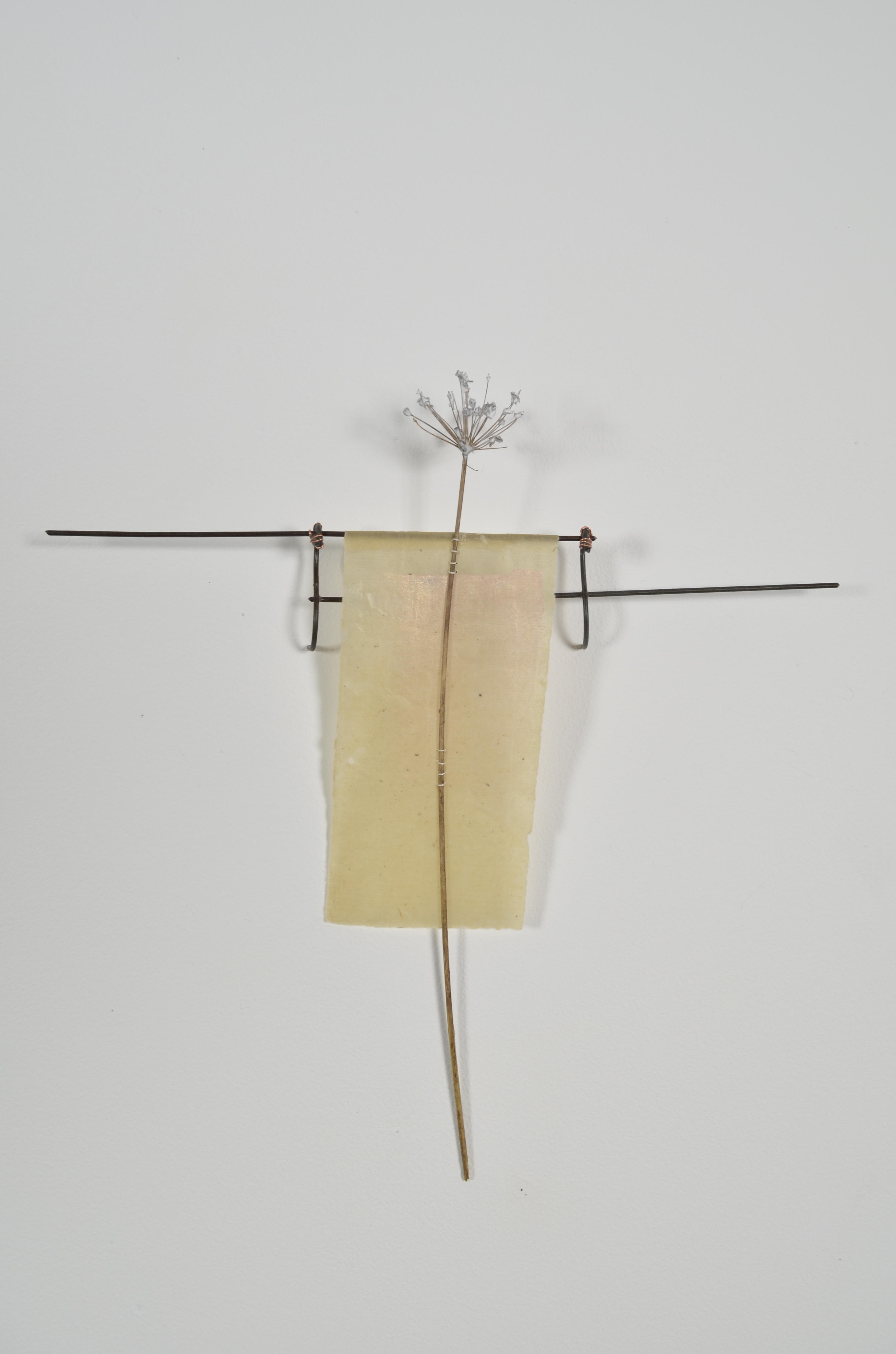 Unbleached mulberry paper with water color is sealed in encaustic, wrapped liked a paper doll dress over the found fence section of arms with an allium sealed in encaustic is sewn on top of the dress.