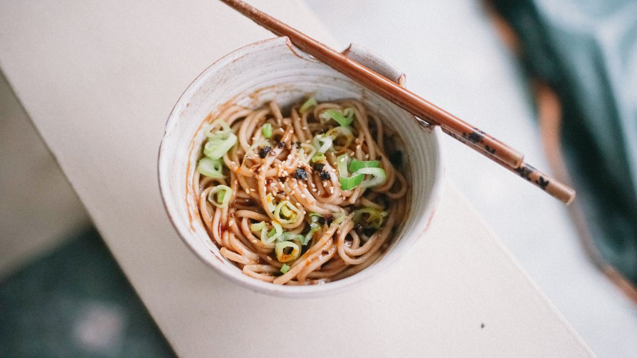 Peanut butter noodles in bowl with chopsticks