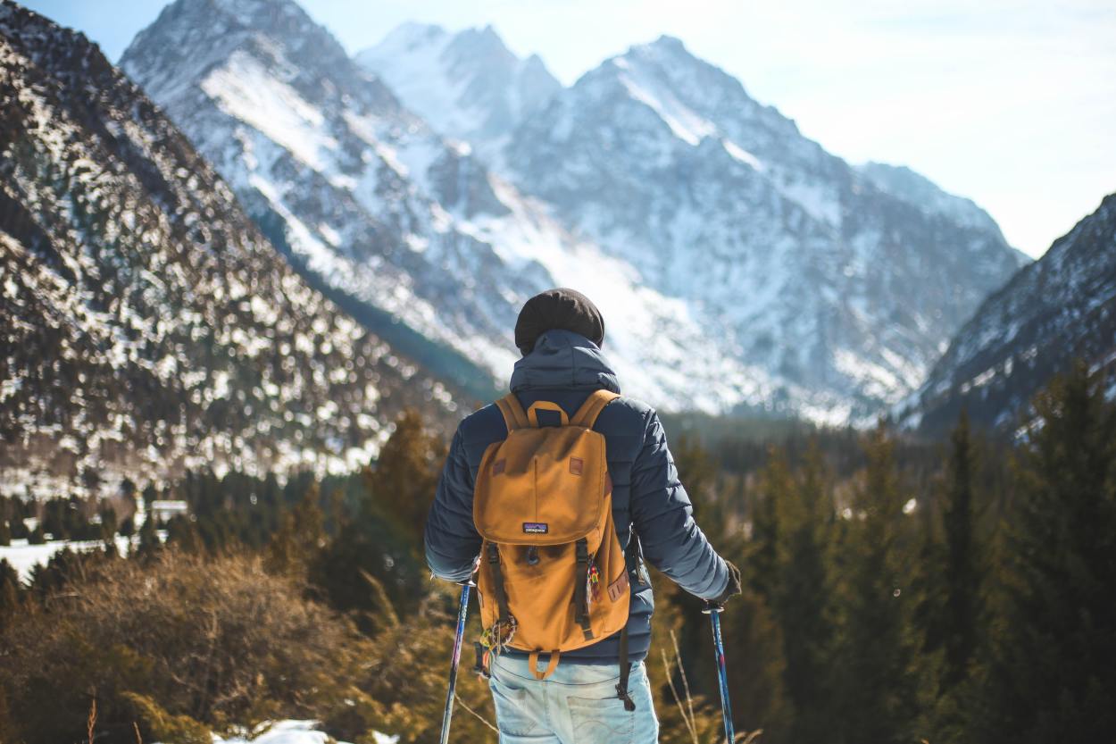 Hiker with trekking poles in snowy mountains