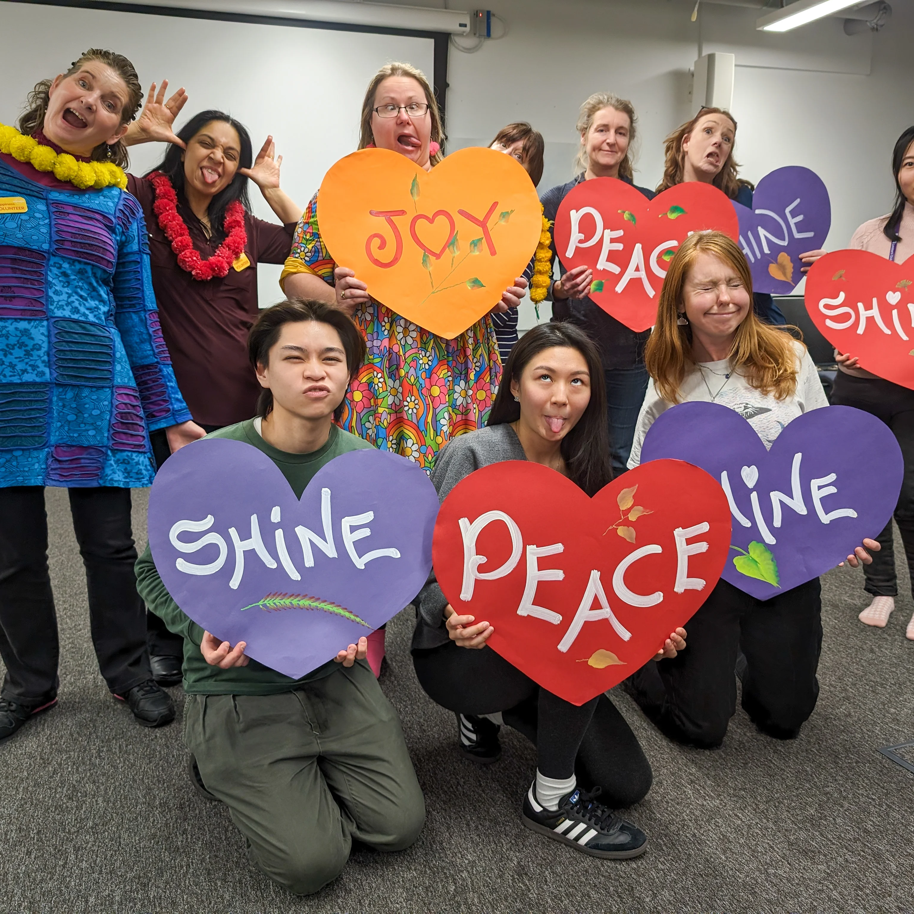 Mindful Workshop  UCL group Mindful Workshop group photo of people pulling silly faces holding signs saying love and shine and happiness