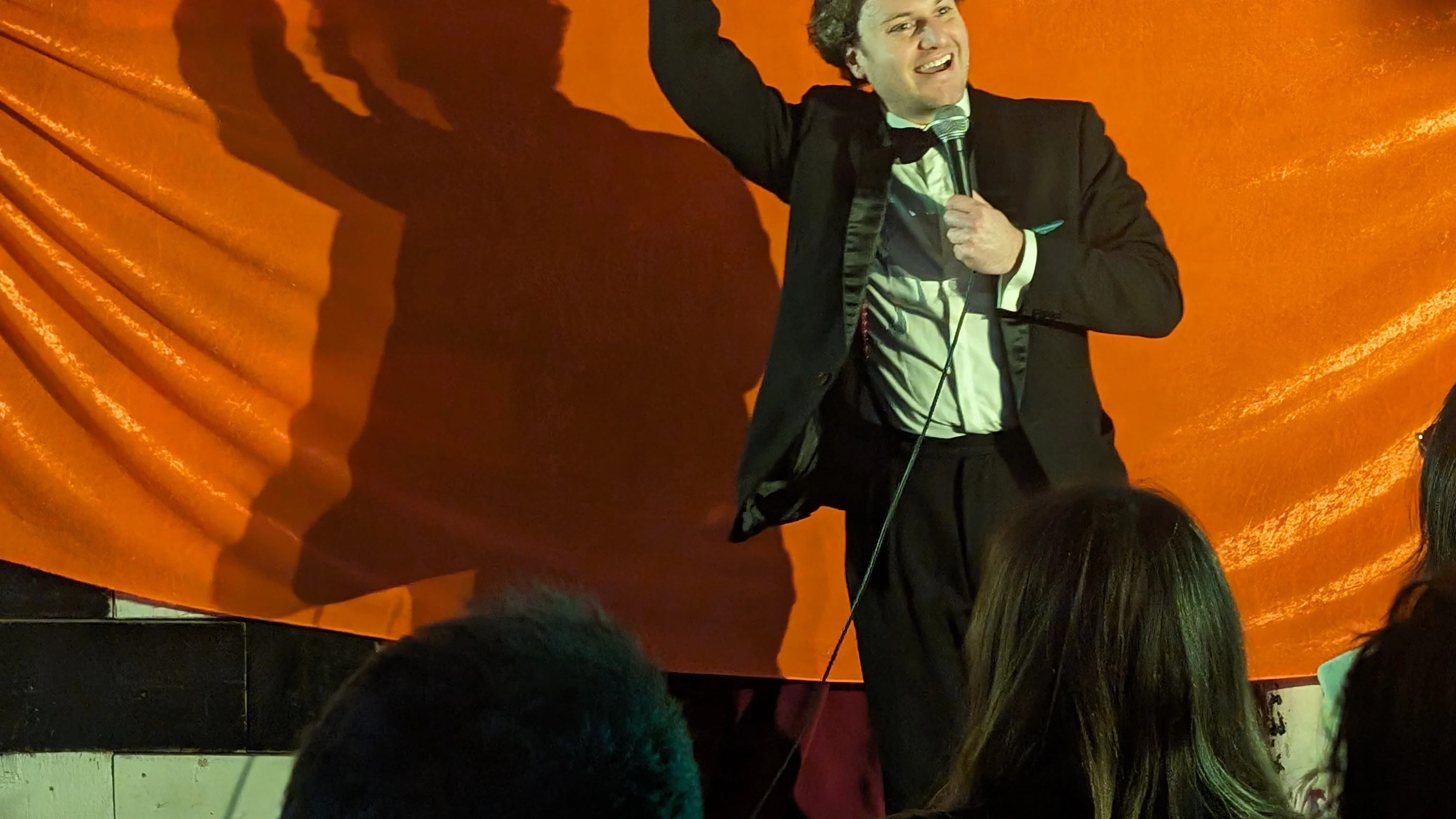 Jonathan Oldfield Comedian on stage holding a microphone