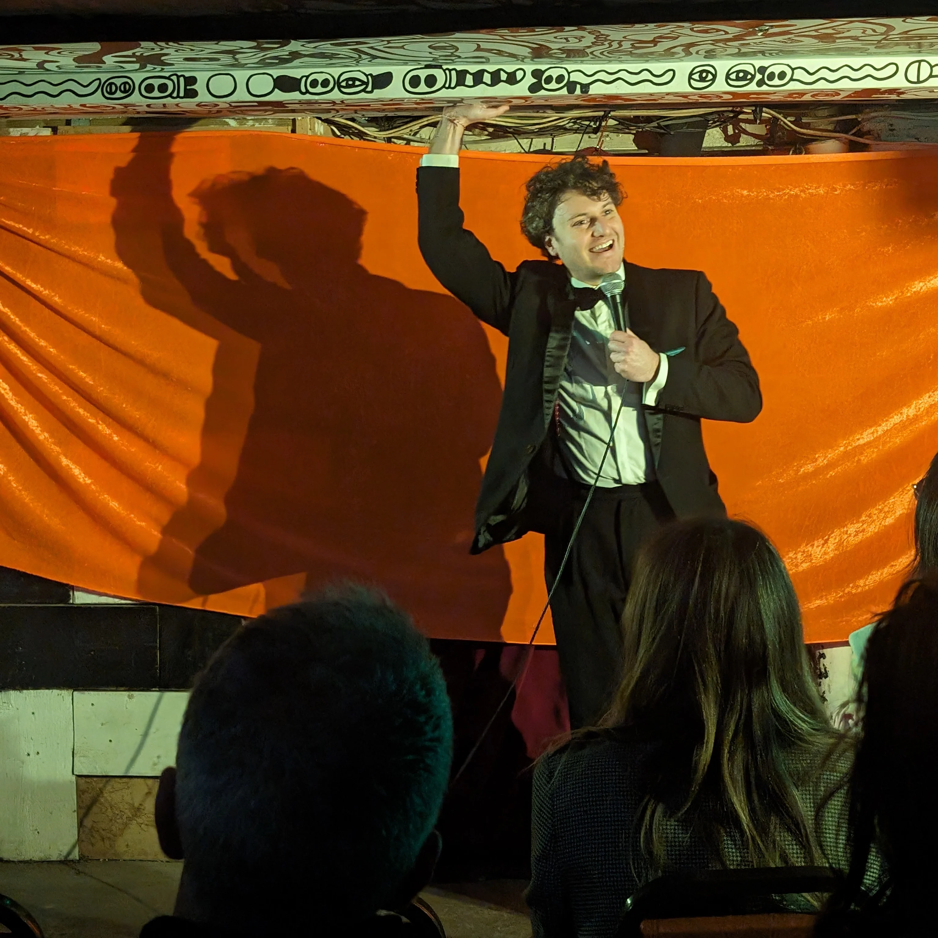 Jonathan Oldfield Comedian on stage holding a microphone