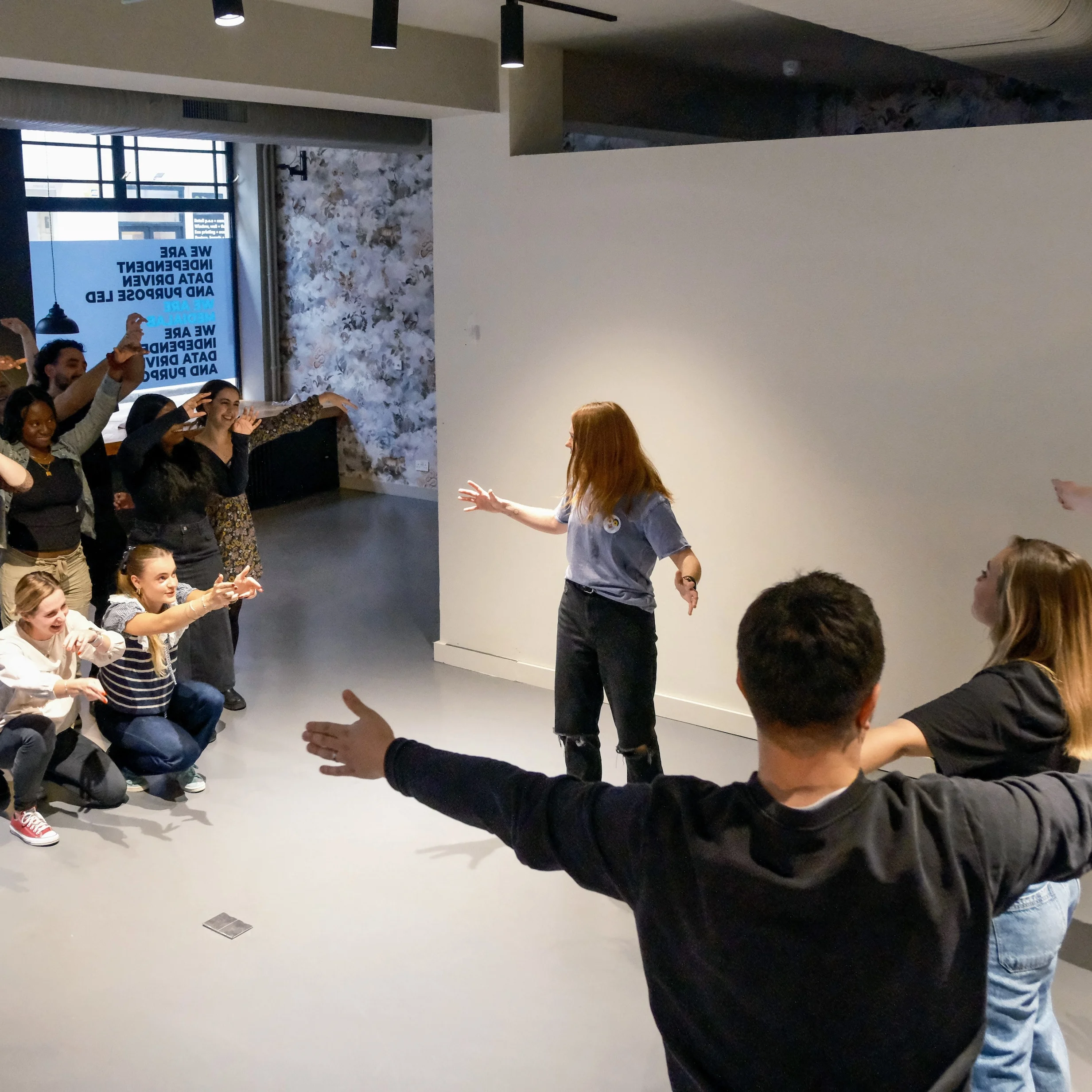 Medialab team workplace training Photo of a group of people making shapes with their bodies in an office environment