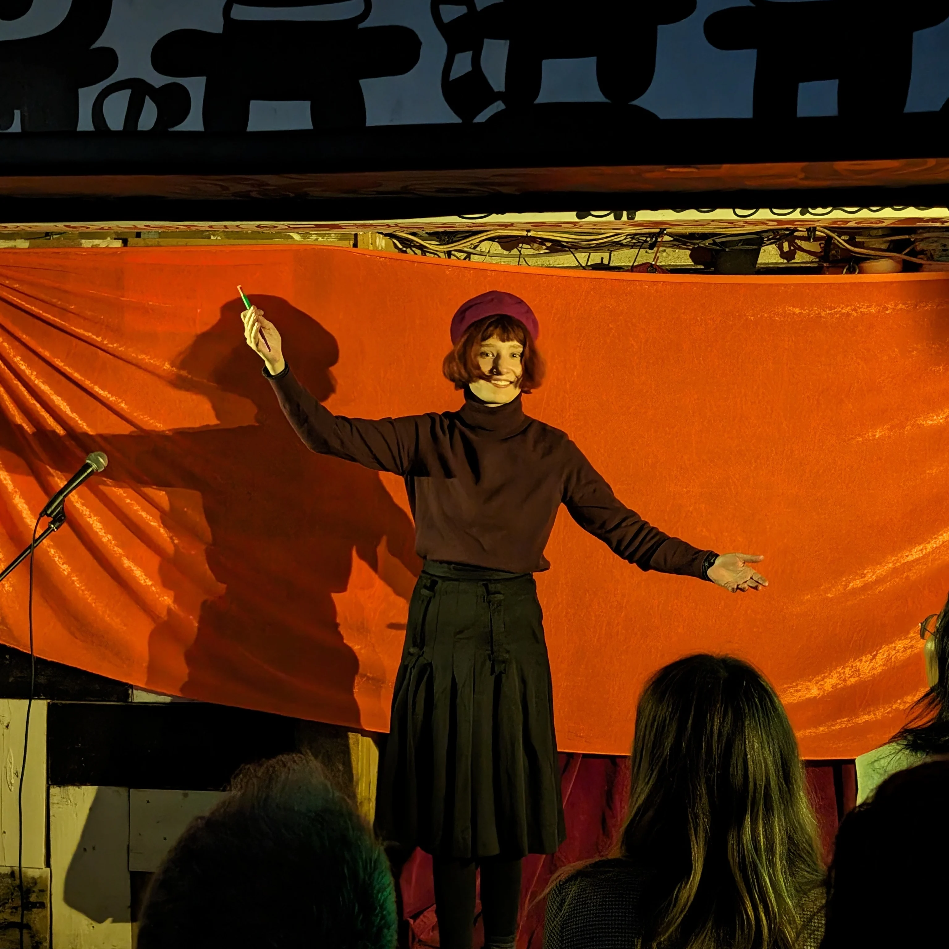 Verity Sharpe Comedian on stage in a beret