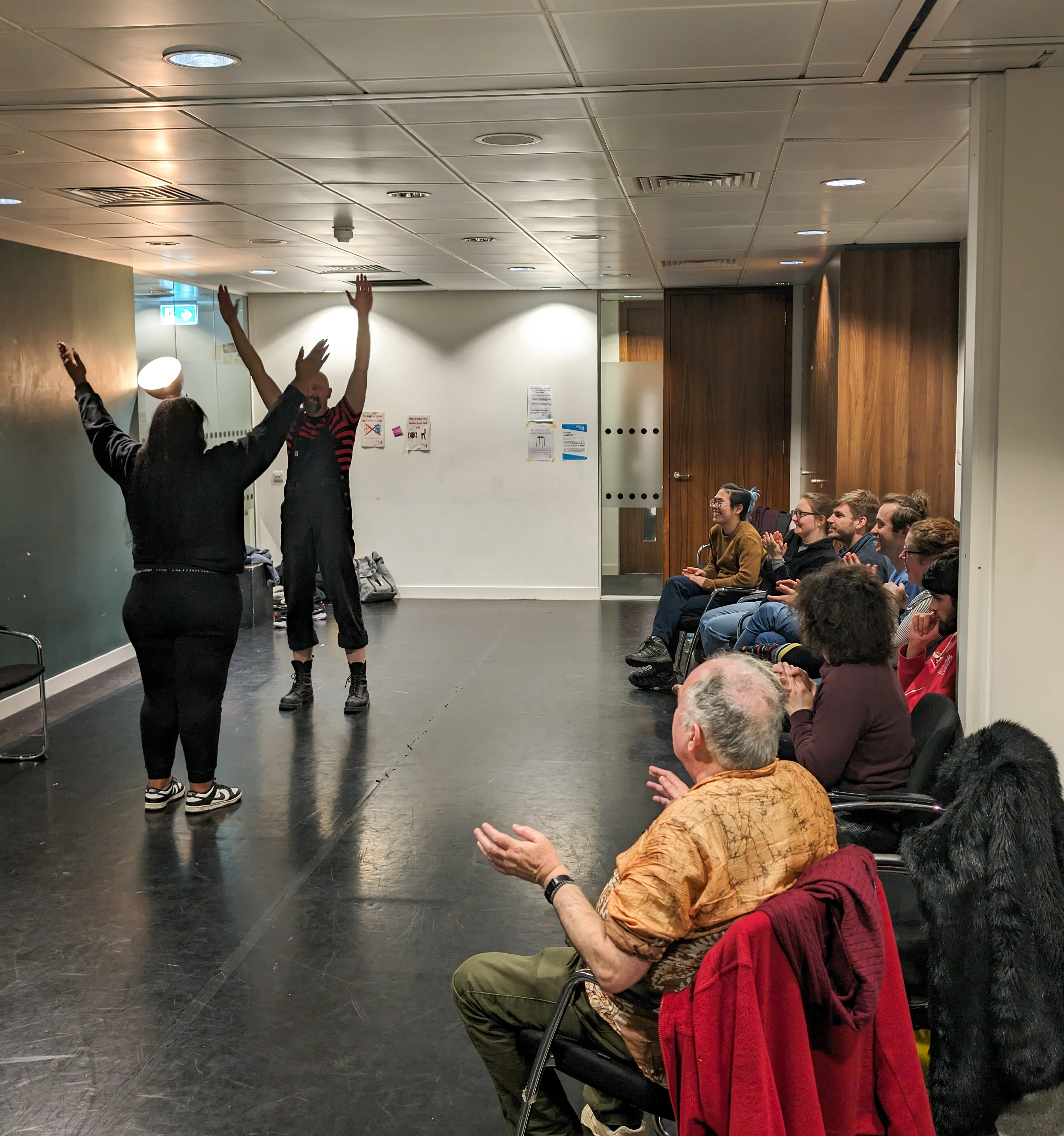Clowning workshop with participants with their arms in the air 
