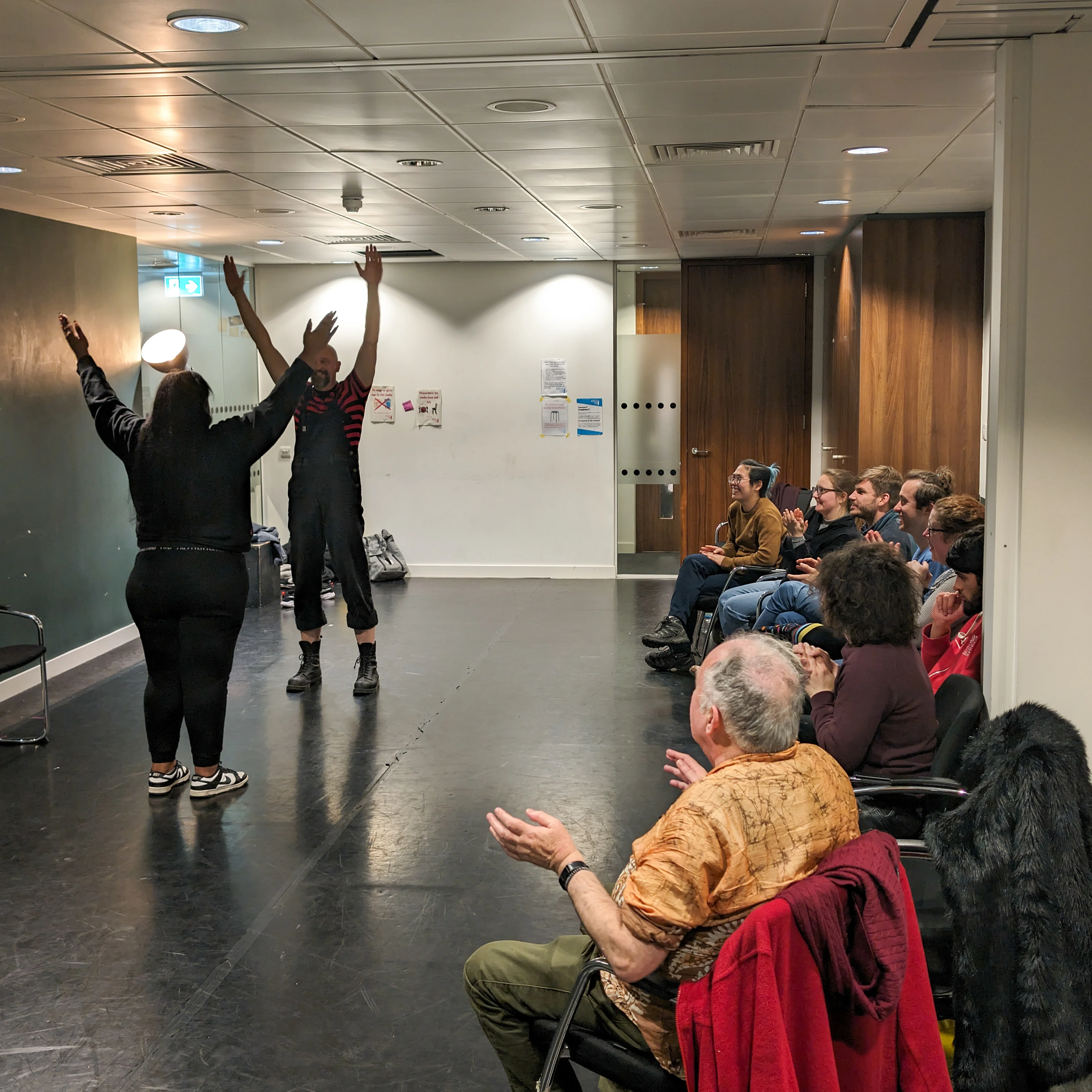 Clowning workshop with participants with their arms in the air 