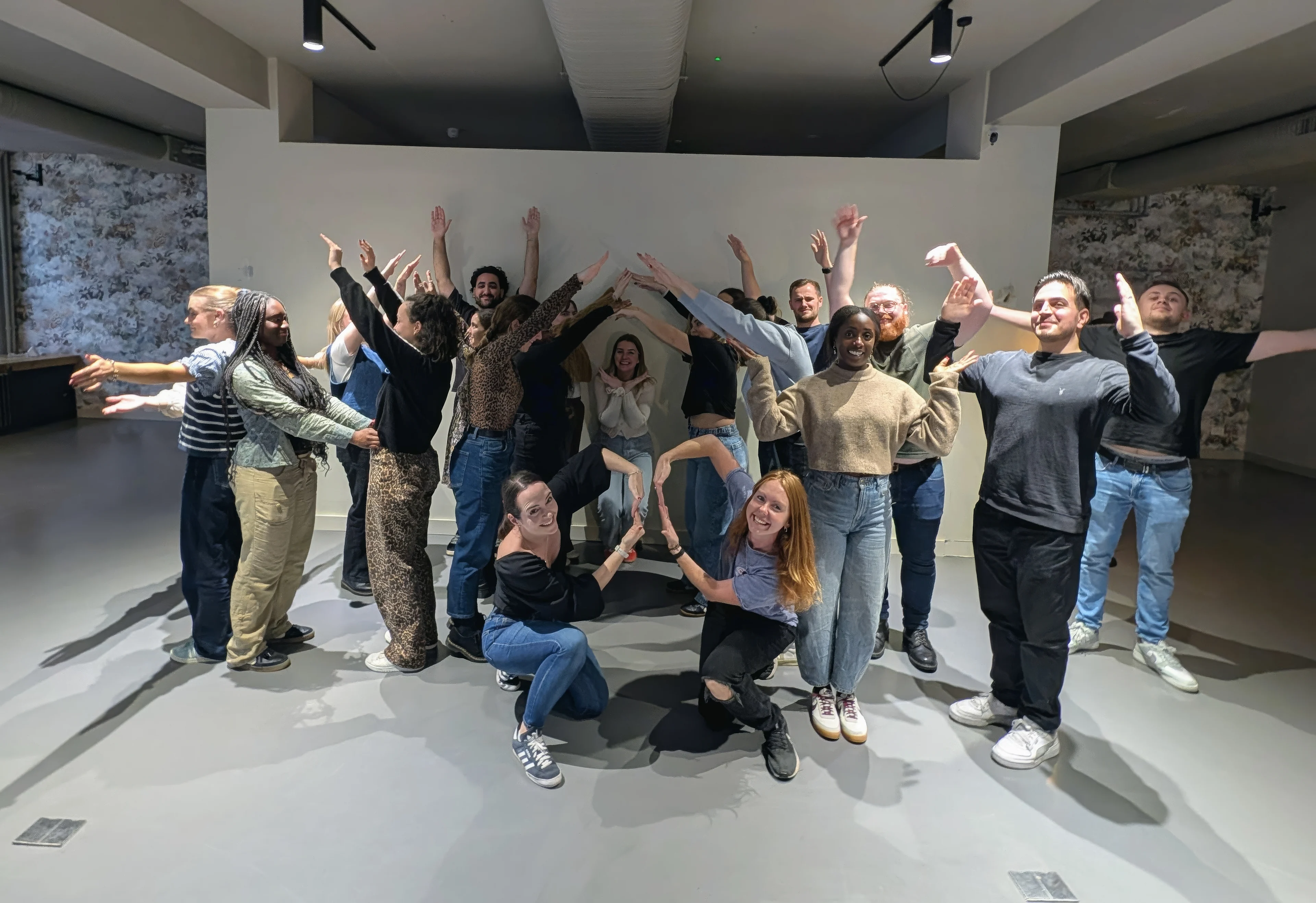 Photo of a group of people making shapes with their bodies in an office environment