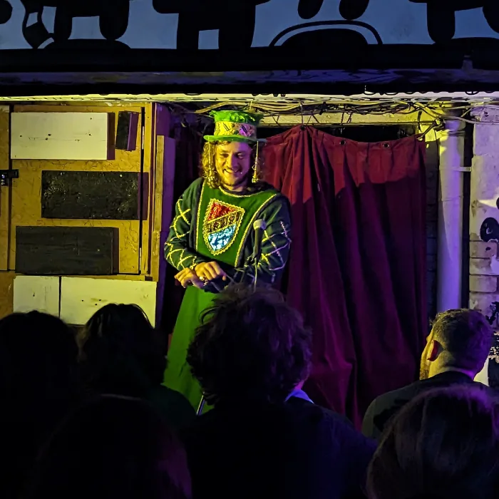 Modern-art-kieran Comedian on stage dressed in green medieval costume
