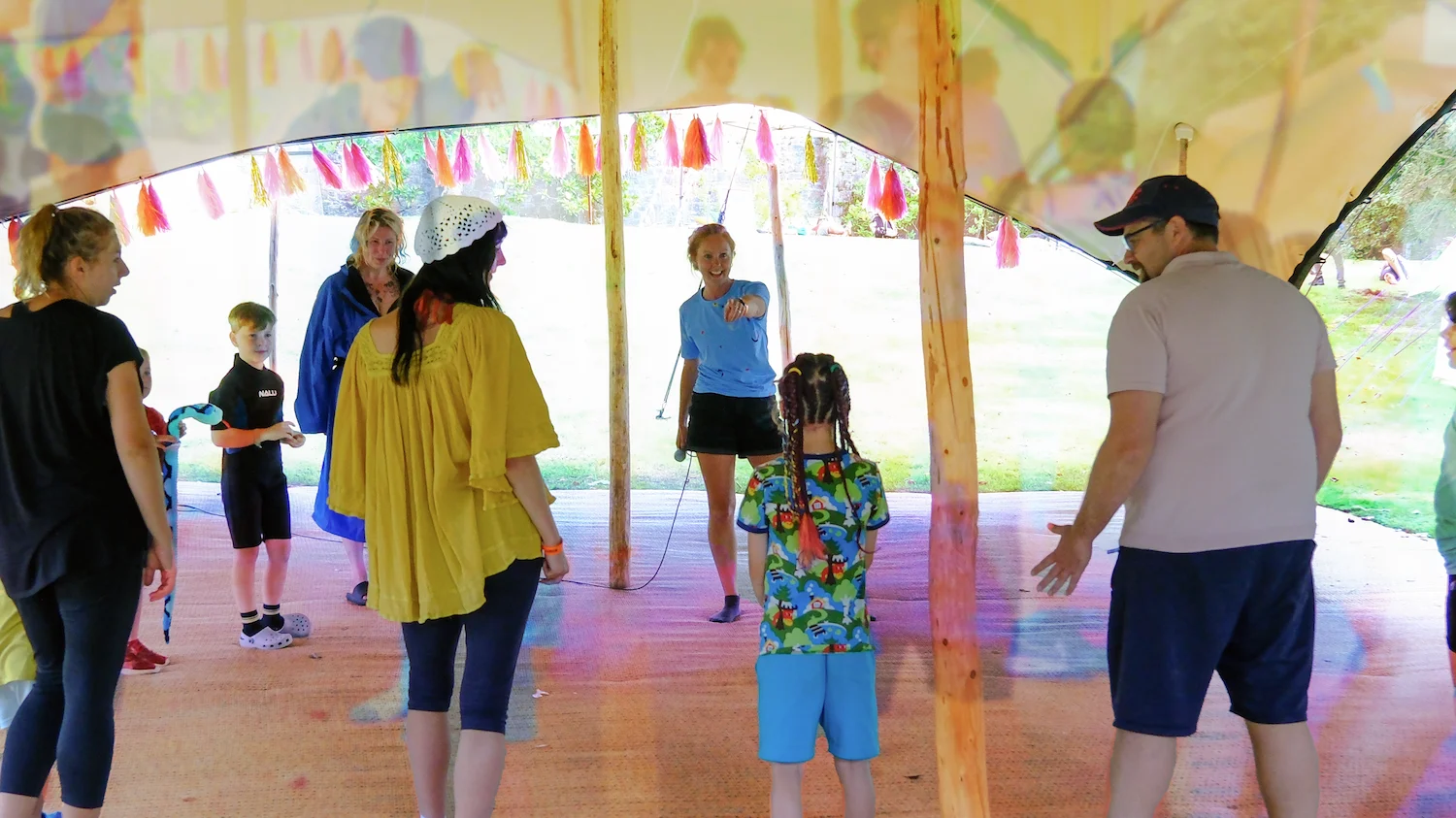Festival workshop with facilitator instructing families  Families stood around in a workshop inside a tipi