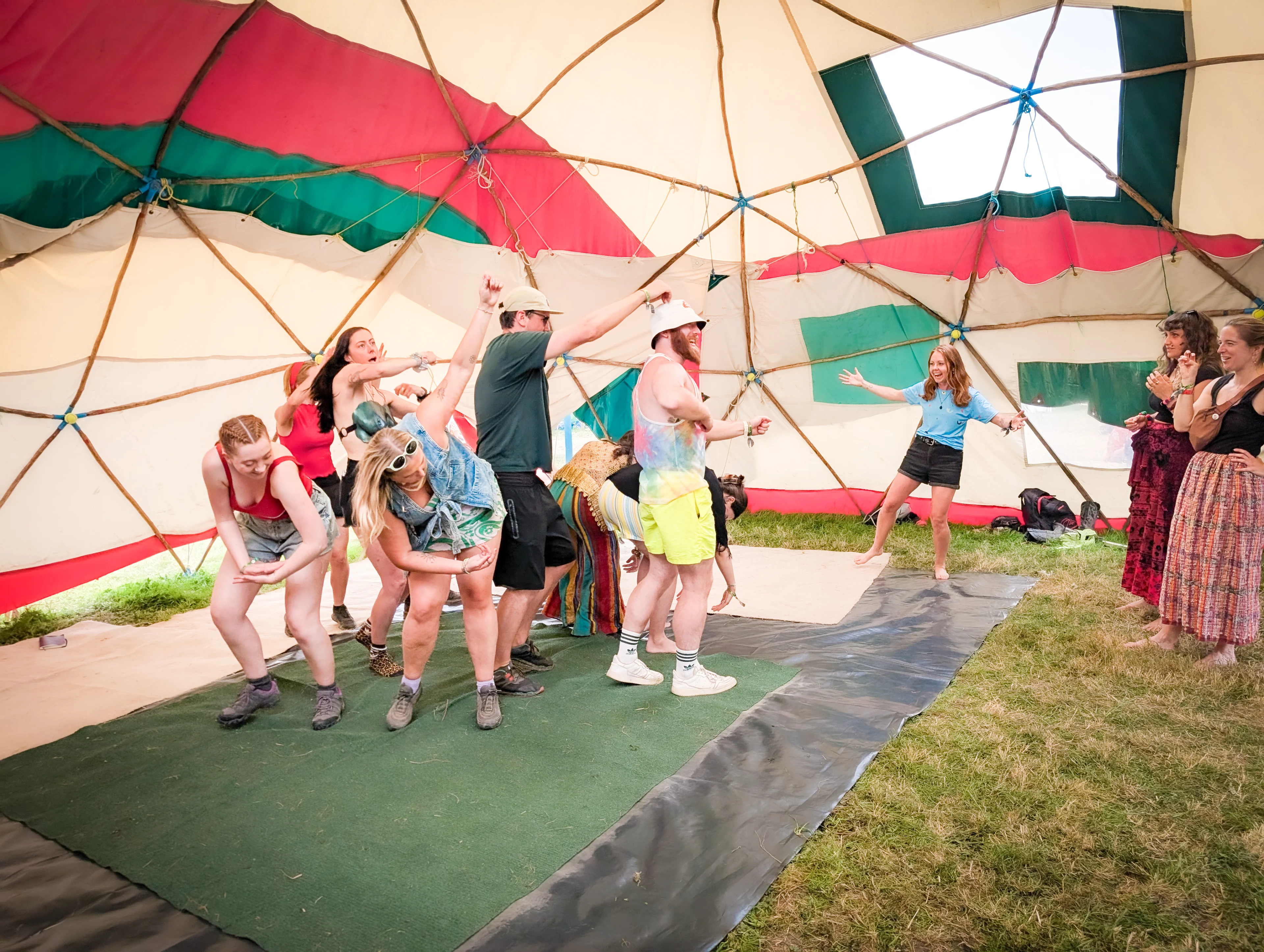 Image shows a group of people making a big shape with their bodies as others watch 