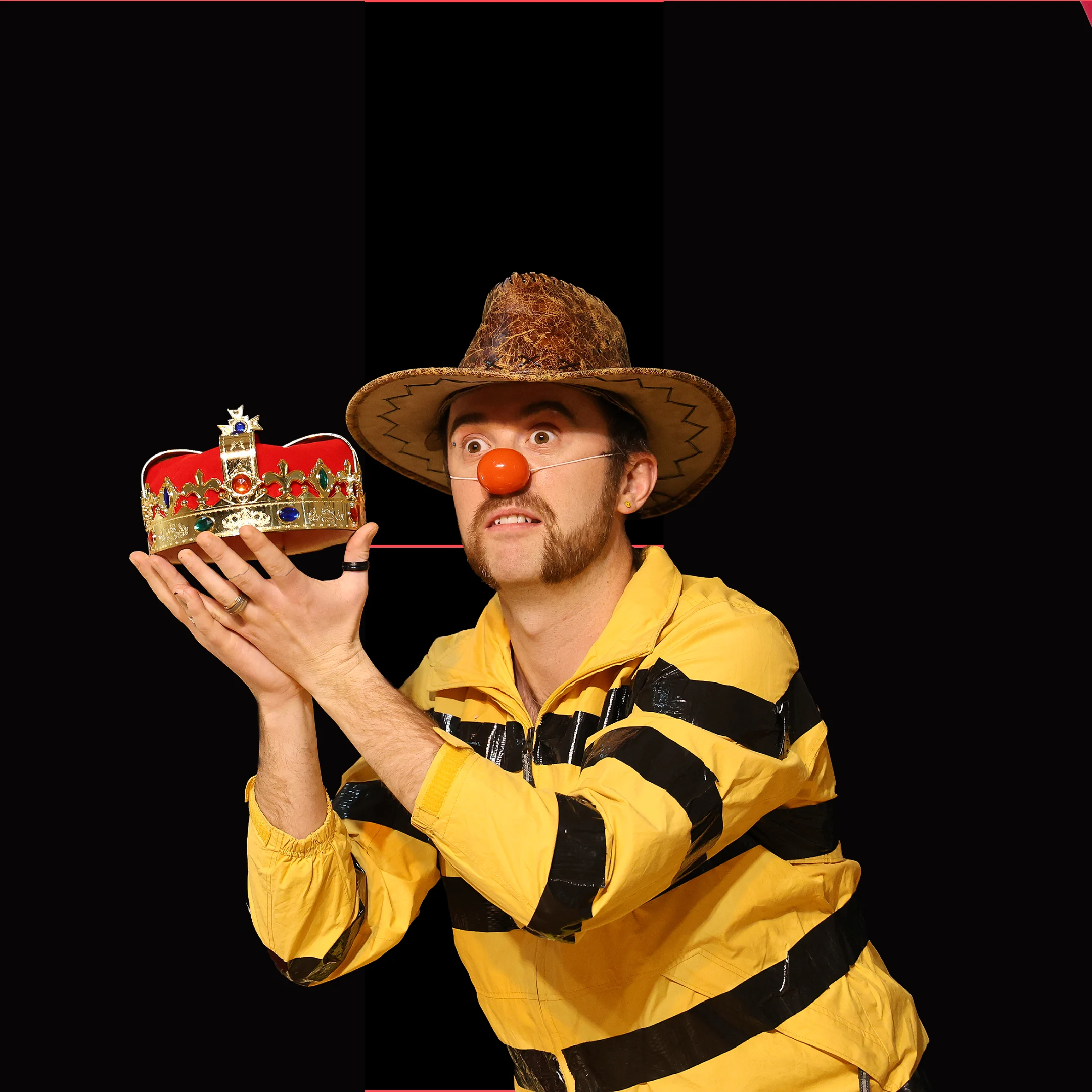 Charlie Jackson Clown Crown Charlie Jackson with a clown nose holding a crown and wearing a yellow and black striped top and a cowboy hat.