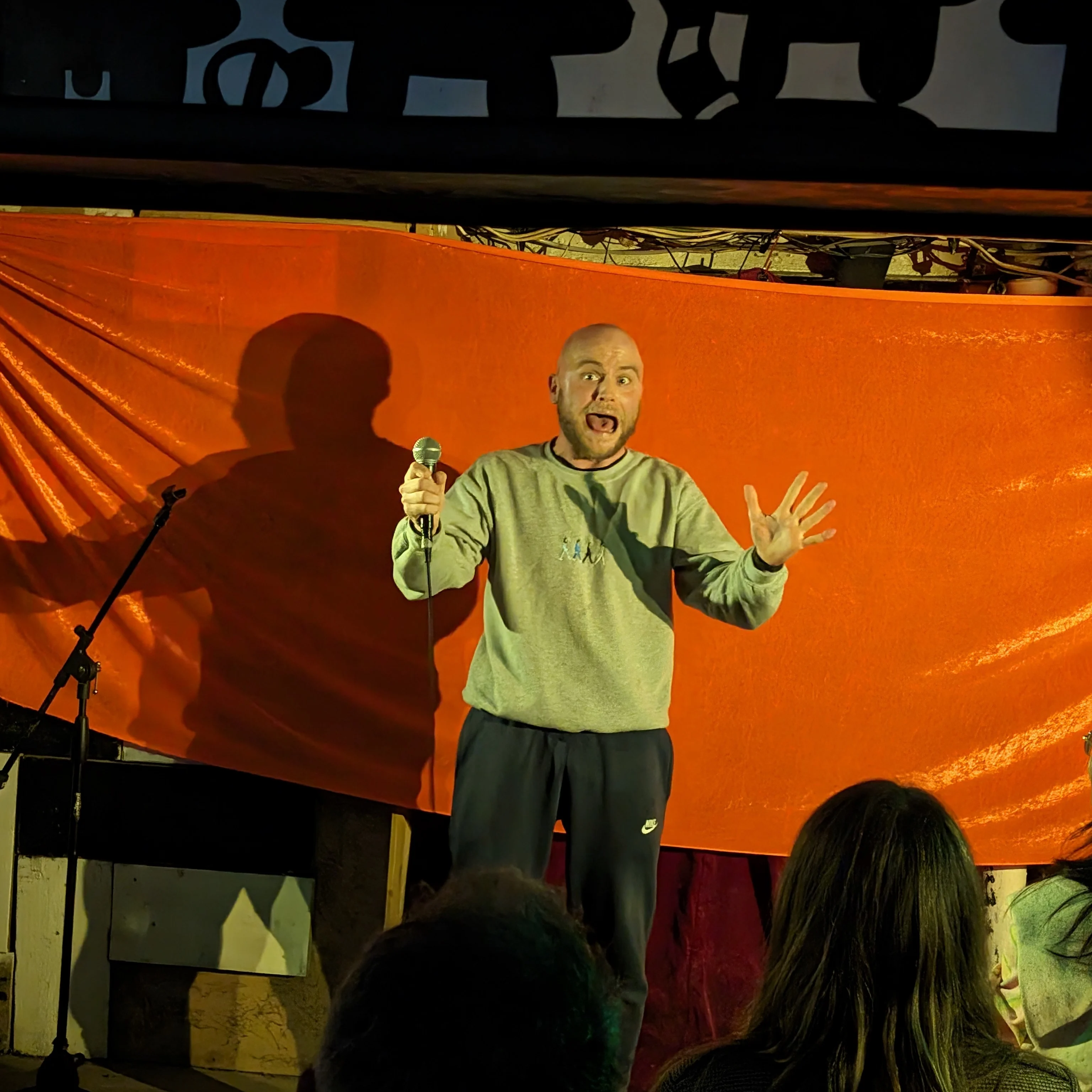 Scott Oswald Comedian on stage holding a microphone