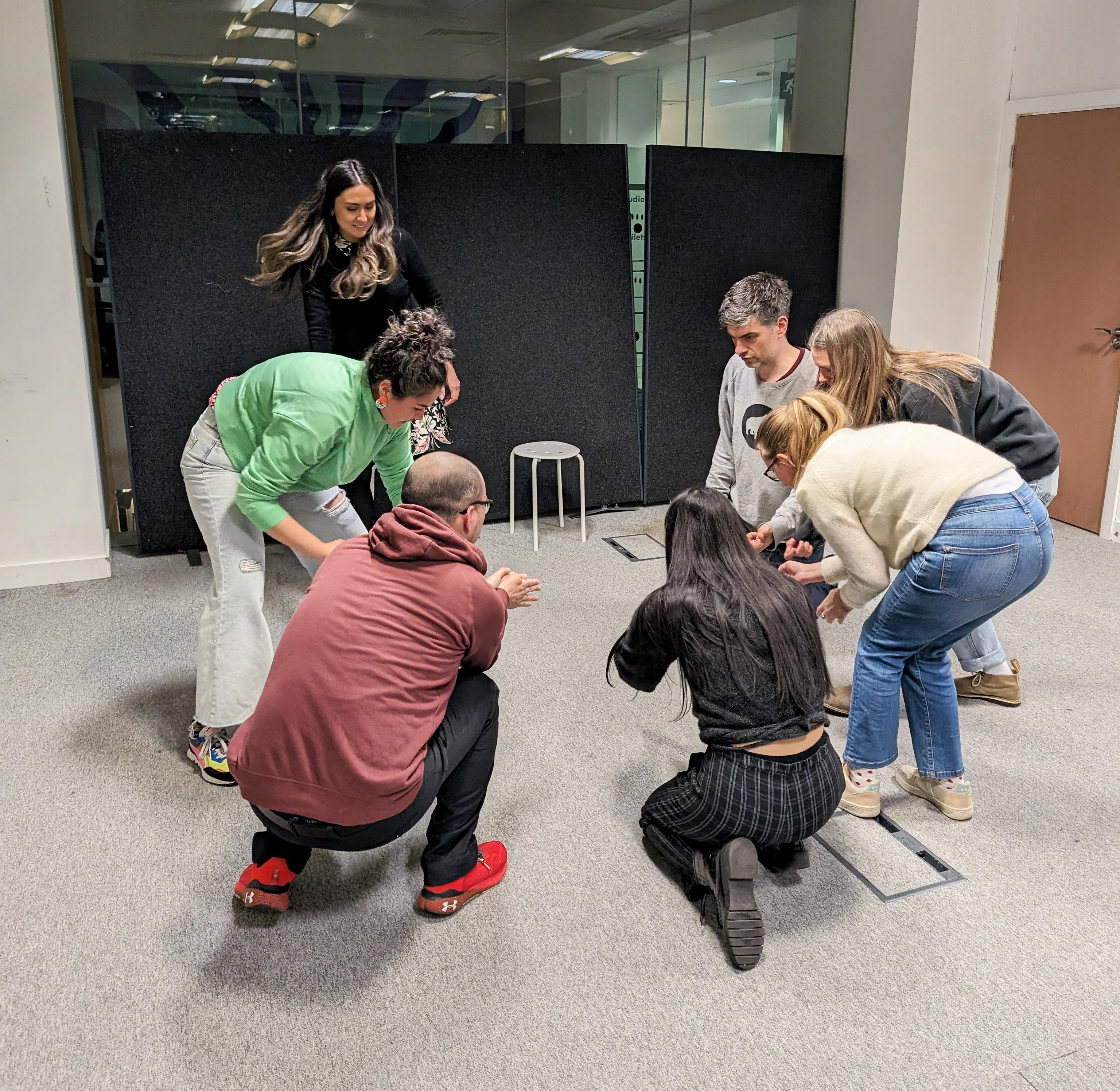 Image of people crouched down on the floor playing 