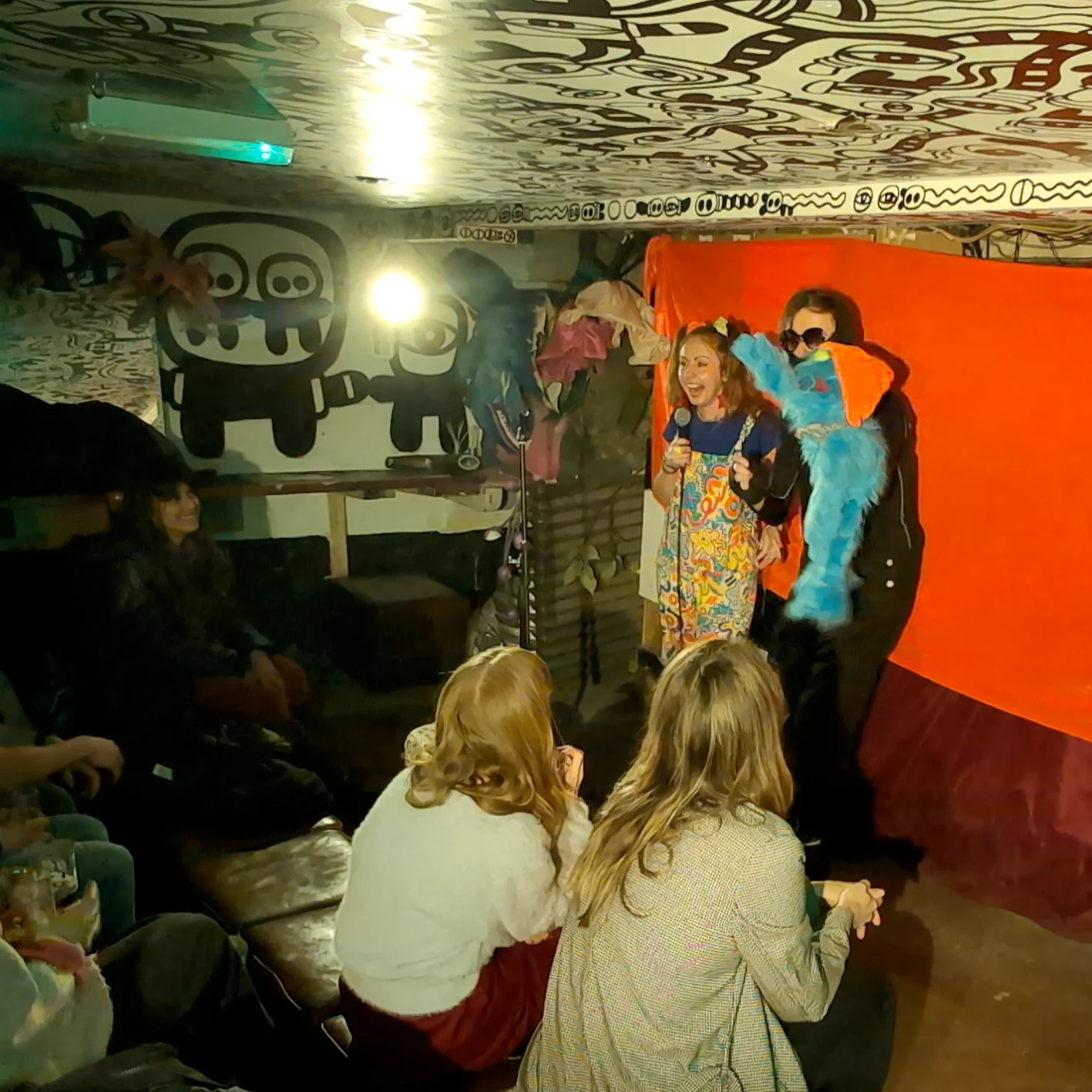 Tony at Modern Art Comedian on stage holding a microphone alongside a big blue puppet