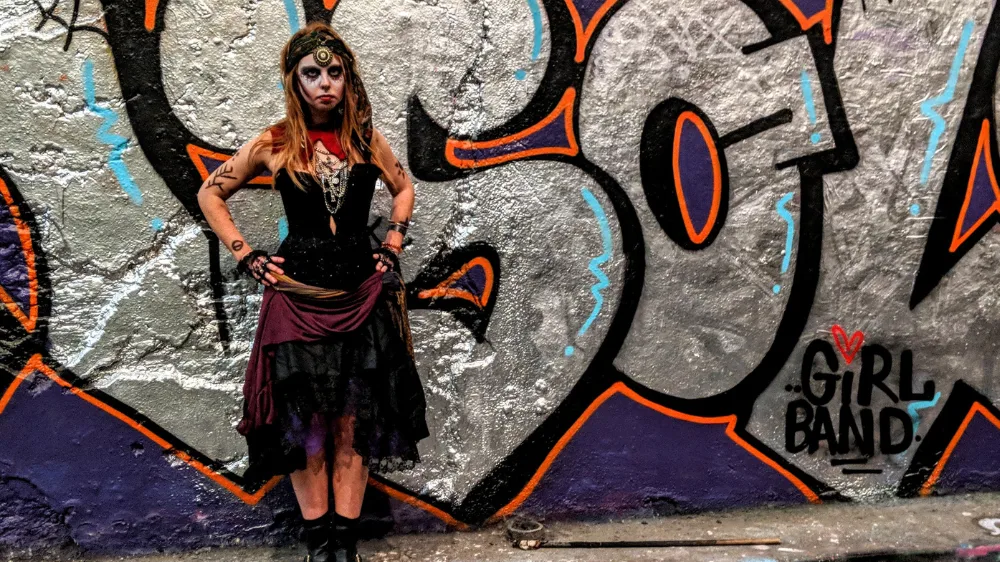 halloween-character-fortune-teller Viki Jackson dressed as a fortune teller with face paint stood with her hands on her hips besides some graffiti
