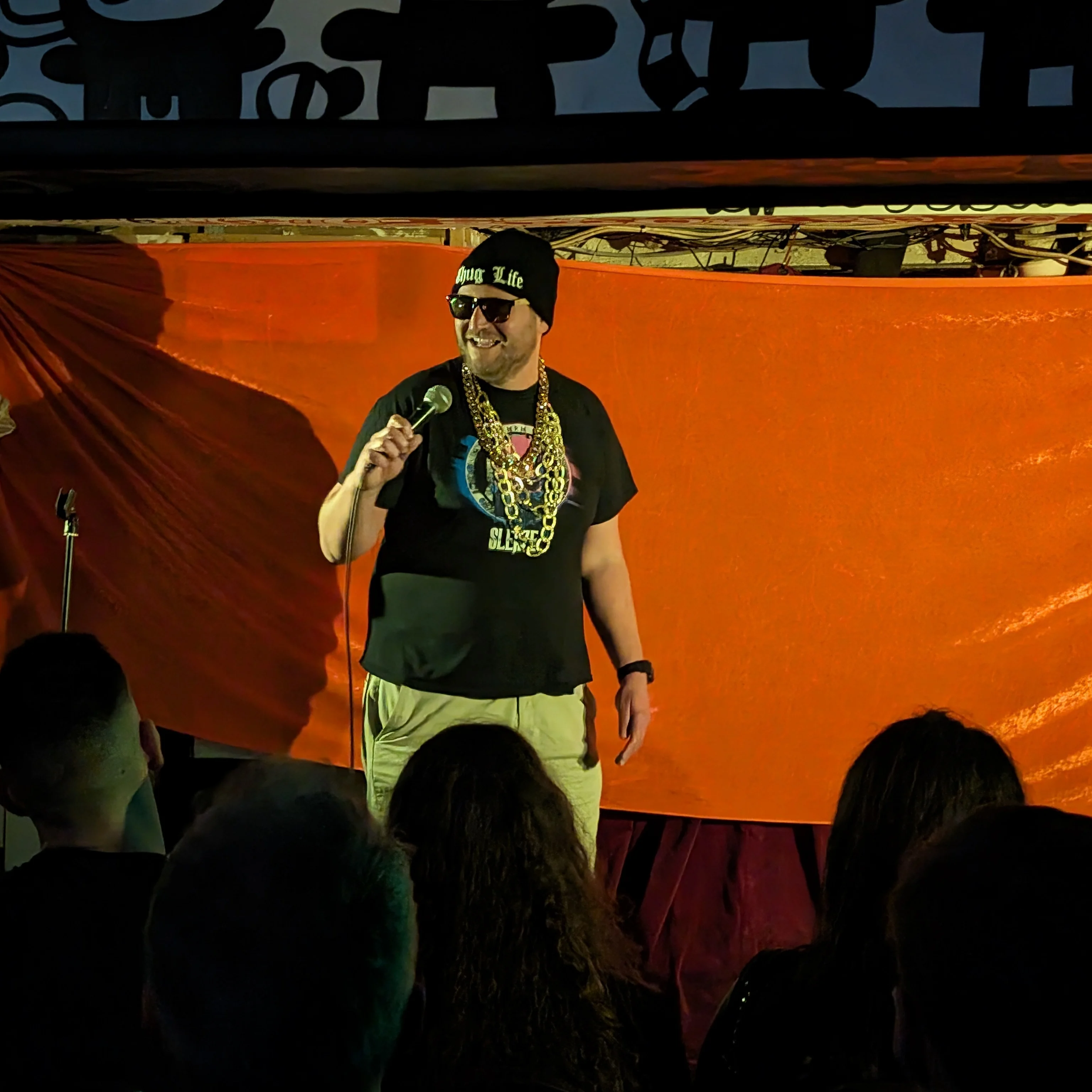 Modern Art LA DE FUNK Comedian on stage holding a microphone