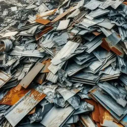 Large pile of scrap metal sheets, stacked haphazardly. The sheets vary in size and are made of zinc, with some displaying signs of rust and wear. The mix of gray, silver, and orange hues gives the scene an industrial and weathered appearance. The edges of the sheets are uneven.