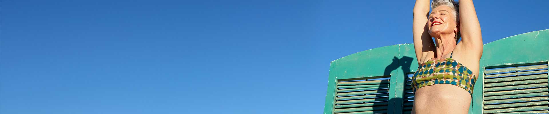 Persona alegre en una playa vistiendo bikini con las manos en el aire