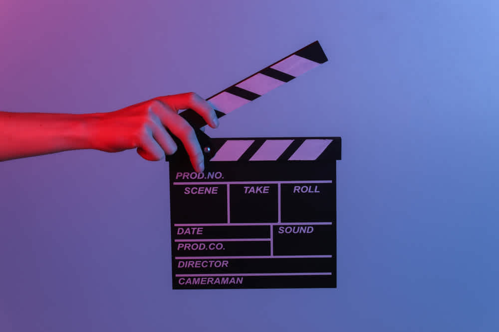 Hand holding film clapper board in blue red neon light. Indicates film shooting