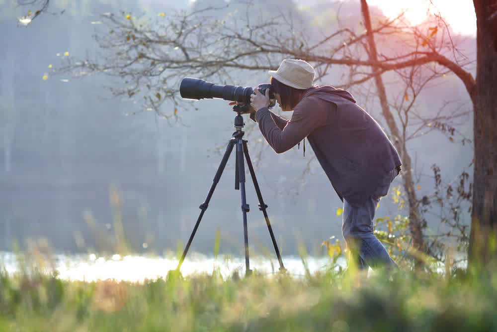 Photographer using telephoto lens in morning light image sourced from Shutterstock