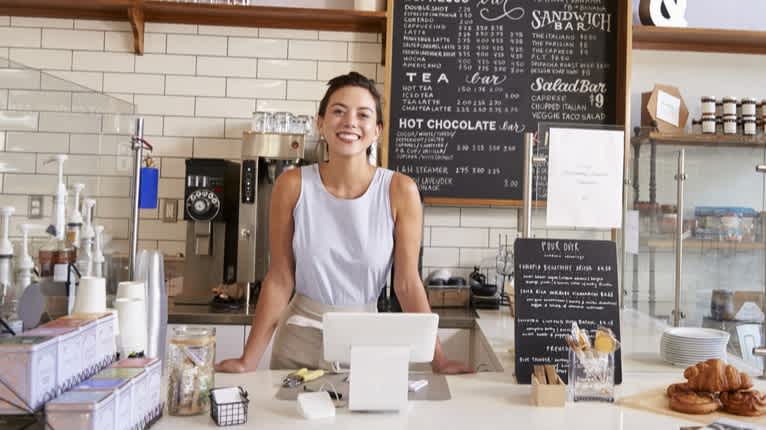 Small business owner smiling at her shop - 4 Types of Small Business Videos That Tell a Story - Clipchamp Blog